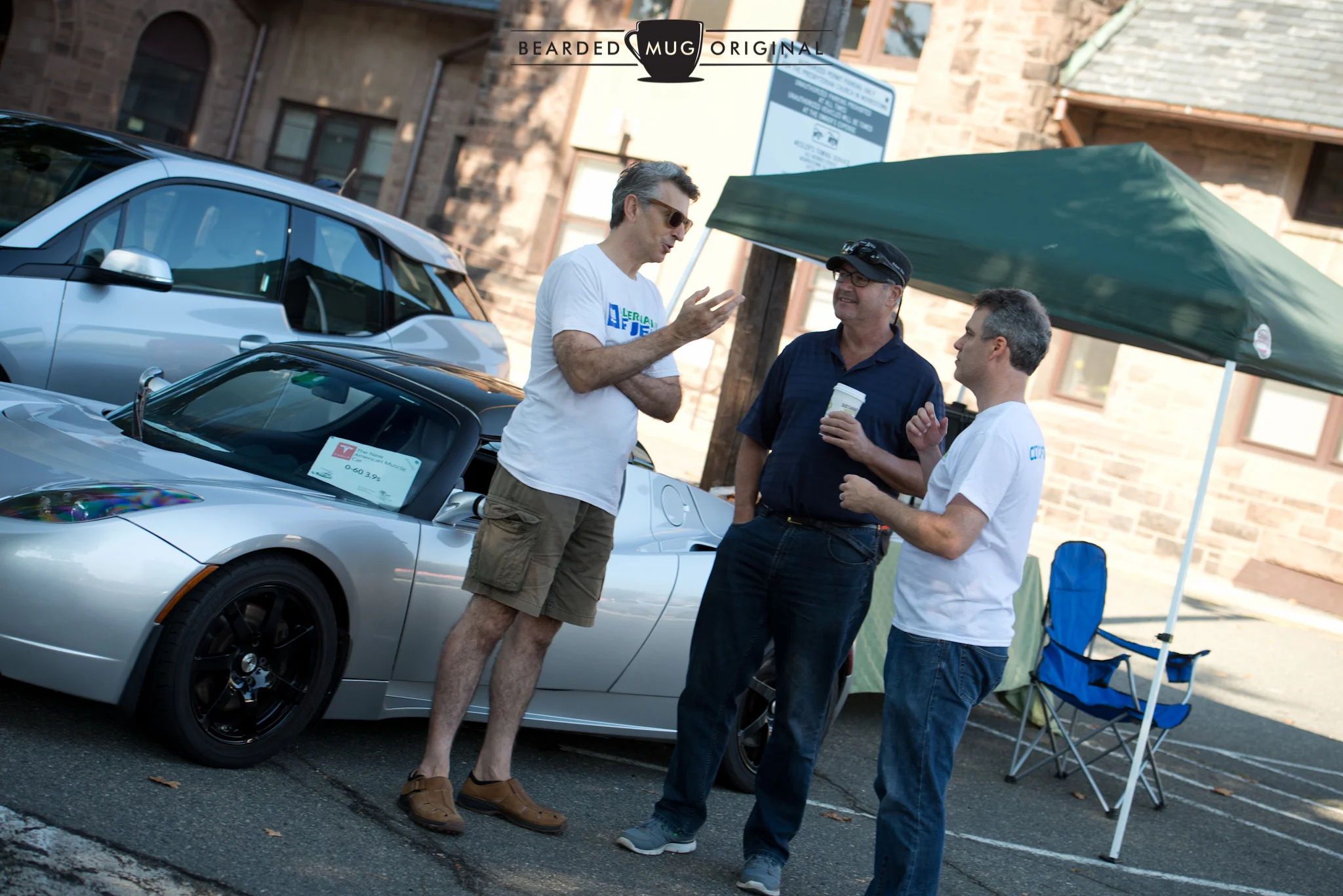 Main organizer Chris Neff (l.) and Paul Miller, president of Sustainable Morristown (r.) discuss the installation of public chargers in town with Morristown's Mayor Tim Dougherty (c.) in front of a Tesla Roadster, the first car offered by the trailblazing marque. 