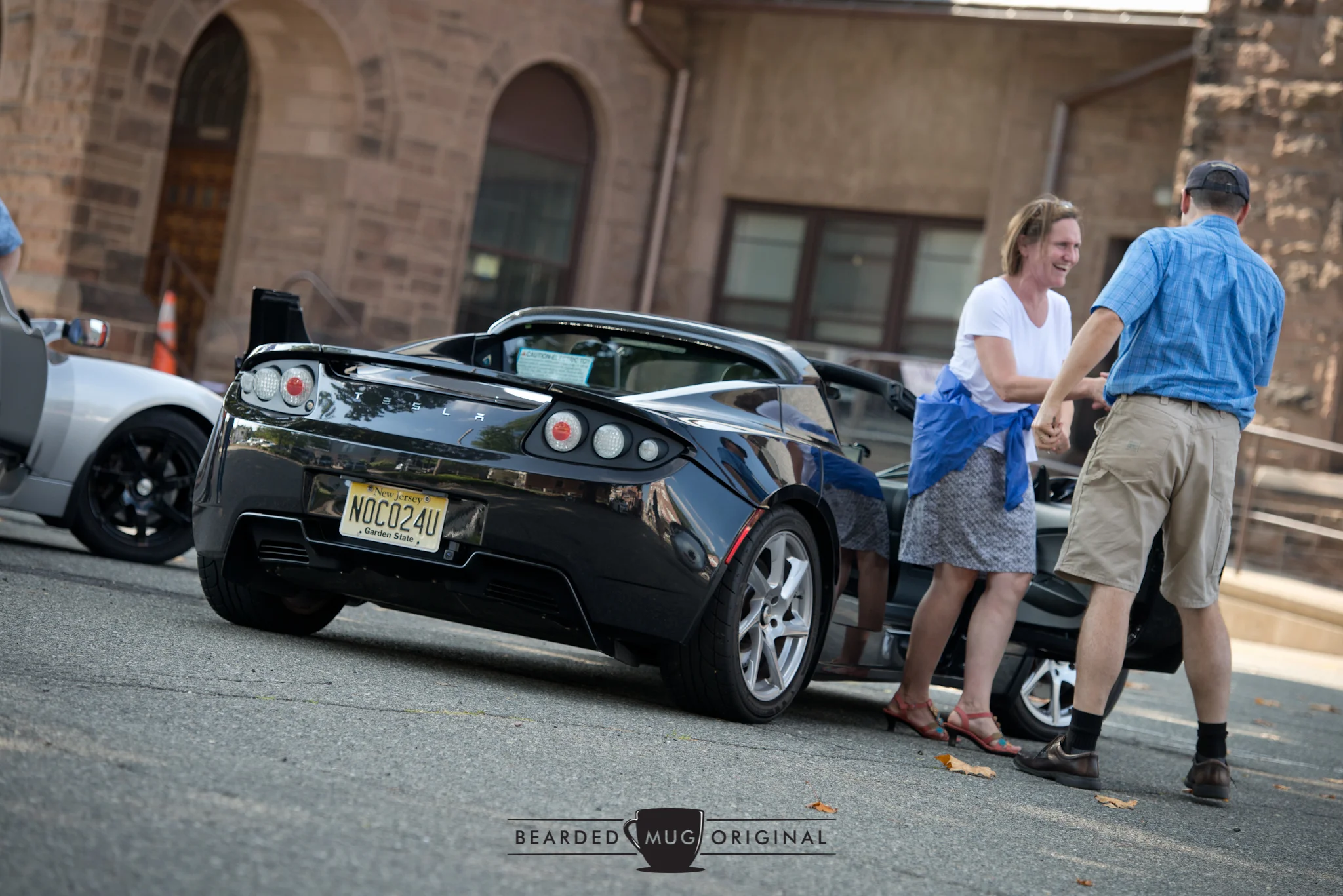 Sarah Stanley is helped out of the Tesla Roadster by its owner, Ian Giblin, after an exhilarating ride through Morristown.