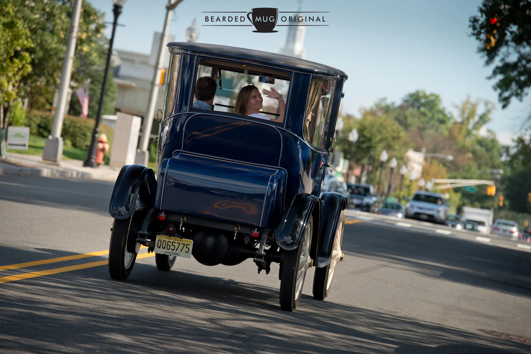 Waving goodbye as they start their 30-minute journey home, in a car powered by batteries, steered by a tiller, and nearing its 100th birthday. 
