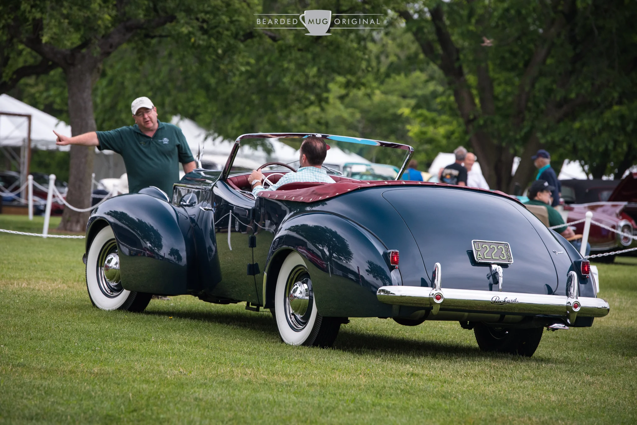 A 1940 Packard Darrin Super Eight Victoria Convertible, from the Marano Collection, is being expertly parked on the show field by one of the many volunteers.