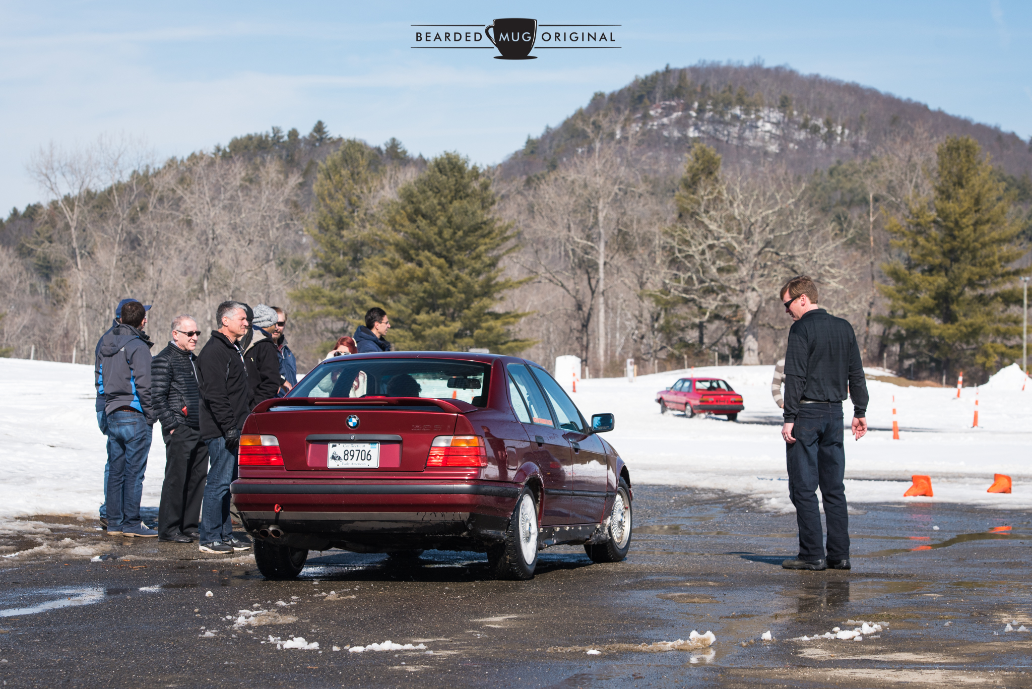 Eager drivers huddle for warmth as they await their turn behind the wheel of the red E36.