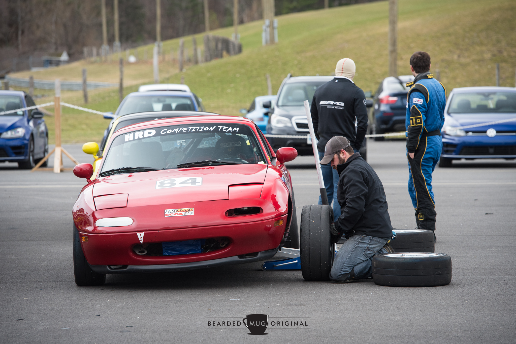 Race-prepped Miata gets some attention in A Paddock, while instructor and driver admire the coalition of Rs.