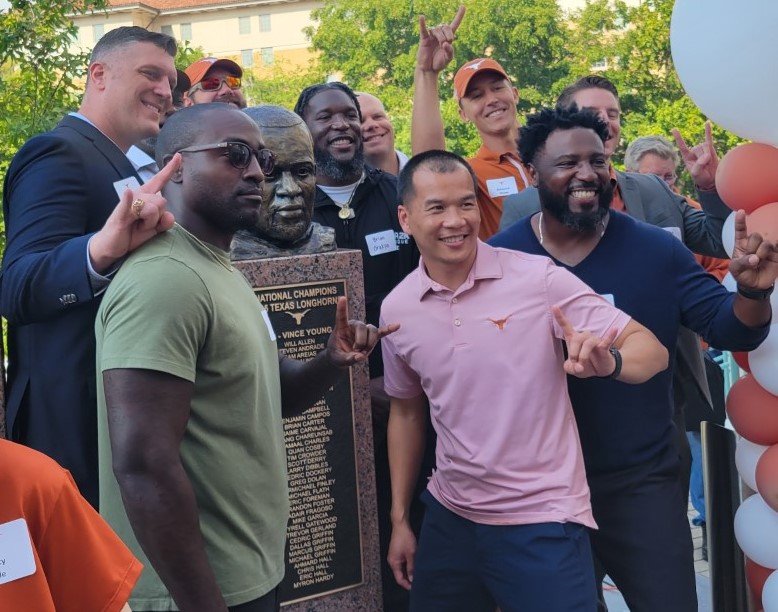  2005 national championship players surround the bust of their quarterback  