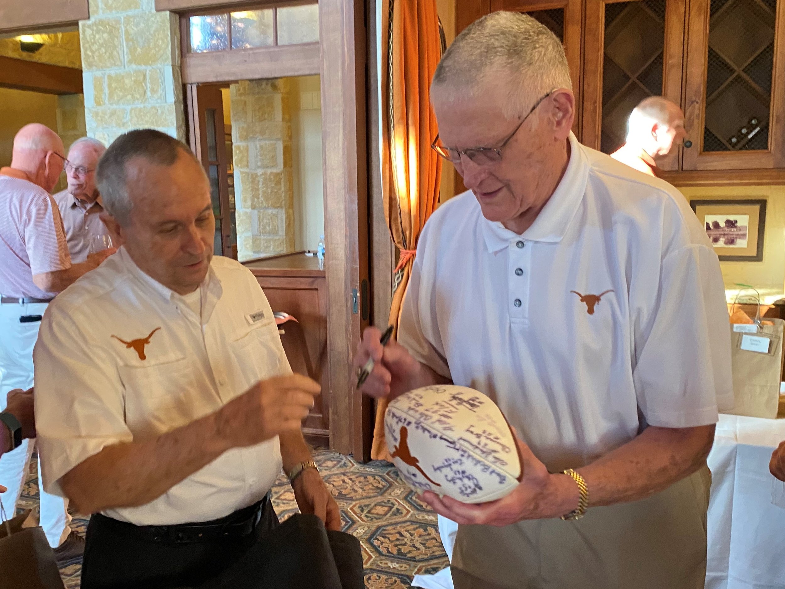 2023 -Staley Faulker, aka Bucket autographs a football for Dr. Bill Clark, an avid fan who made a special wooden plaque for each of the 1963 Longhorns attending the 60th anniversary reunion on September 1 2023.JPG