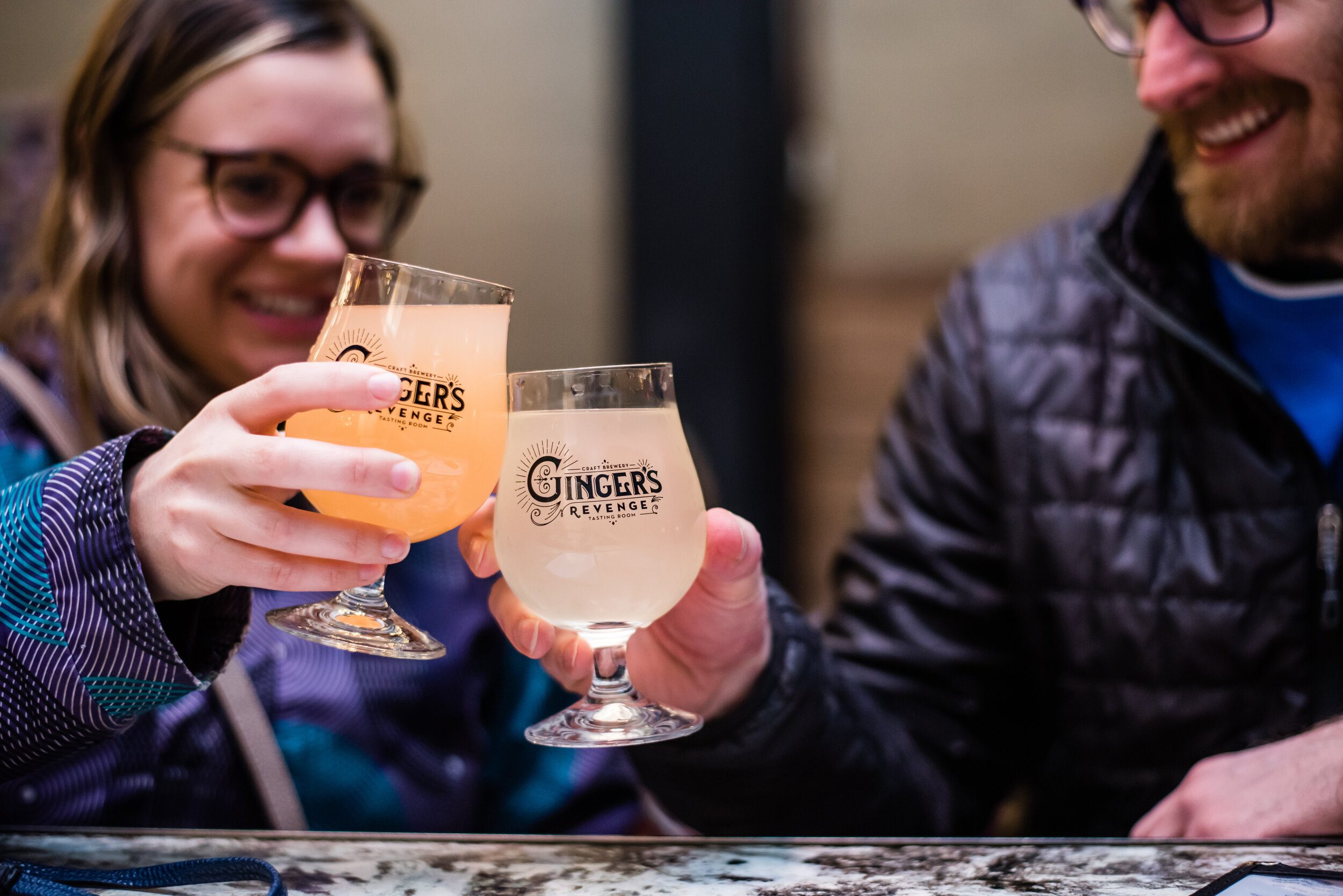 Man and woman cheers with glasses of ginger beer at bar