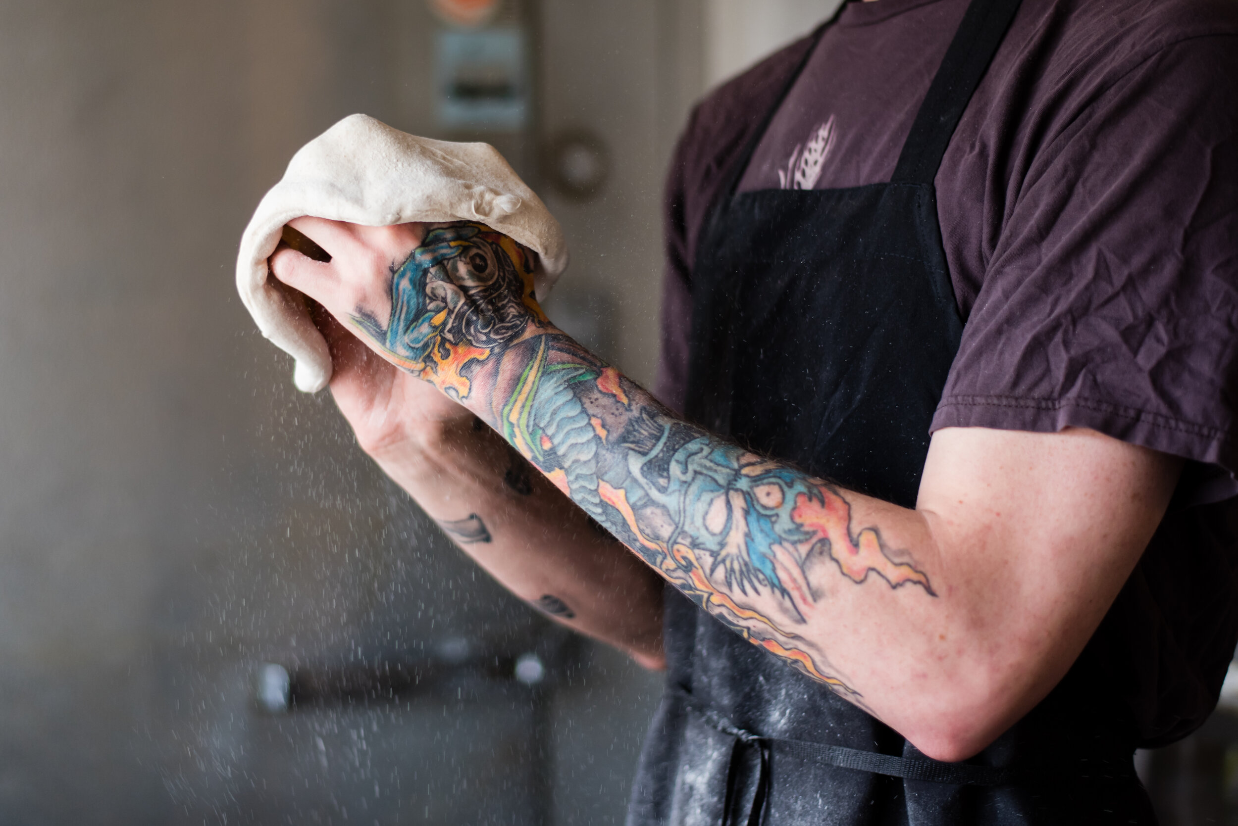 Man with tattoos prepares pizza dough
