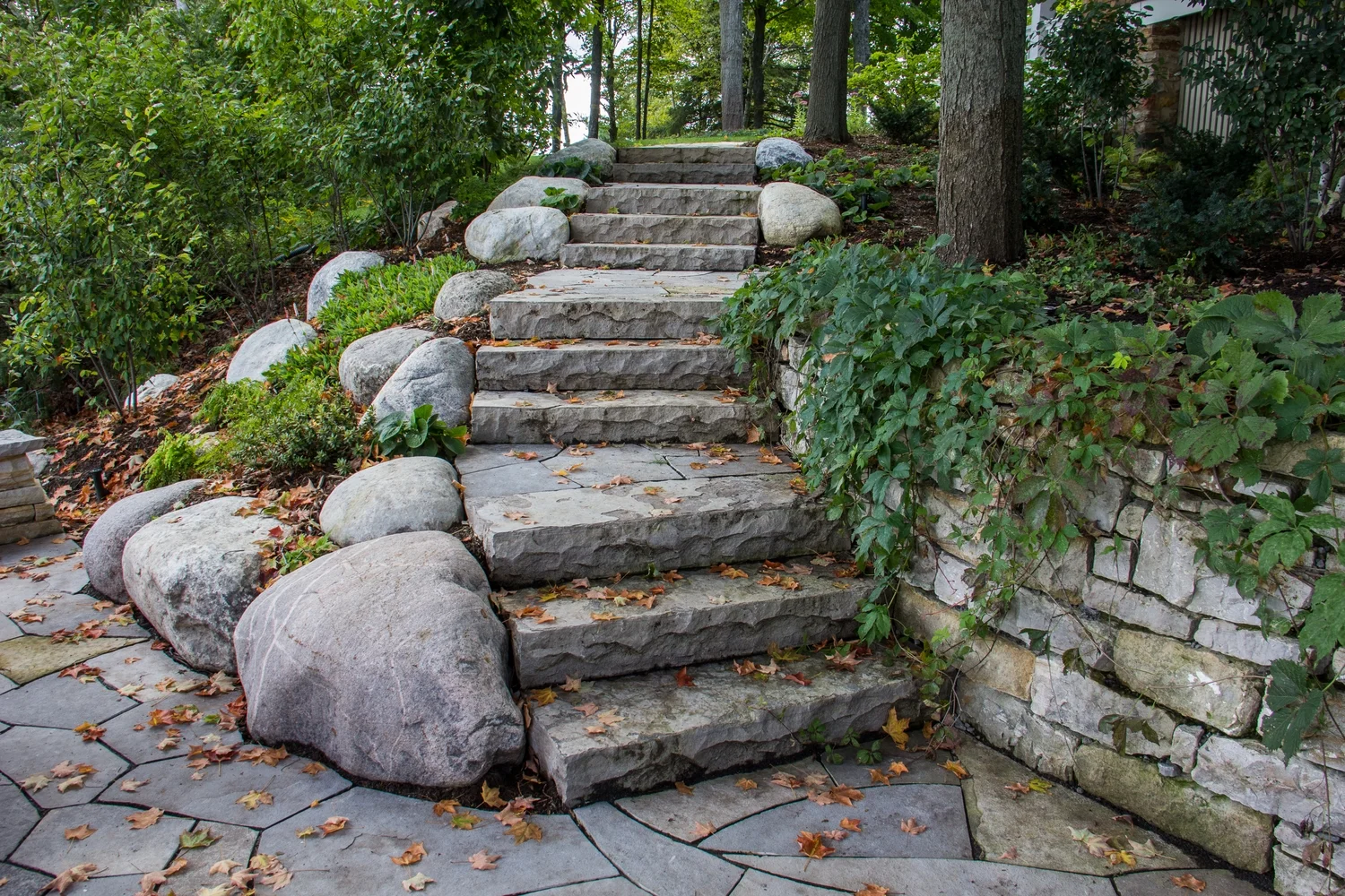 Narural stone steps from owen sound retained with Lanark round boulders. Steps where built into the pre existing wall to the right.