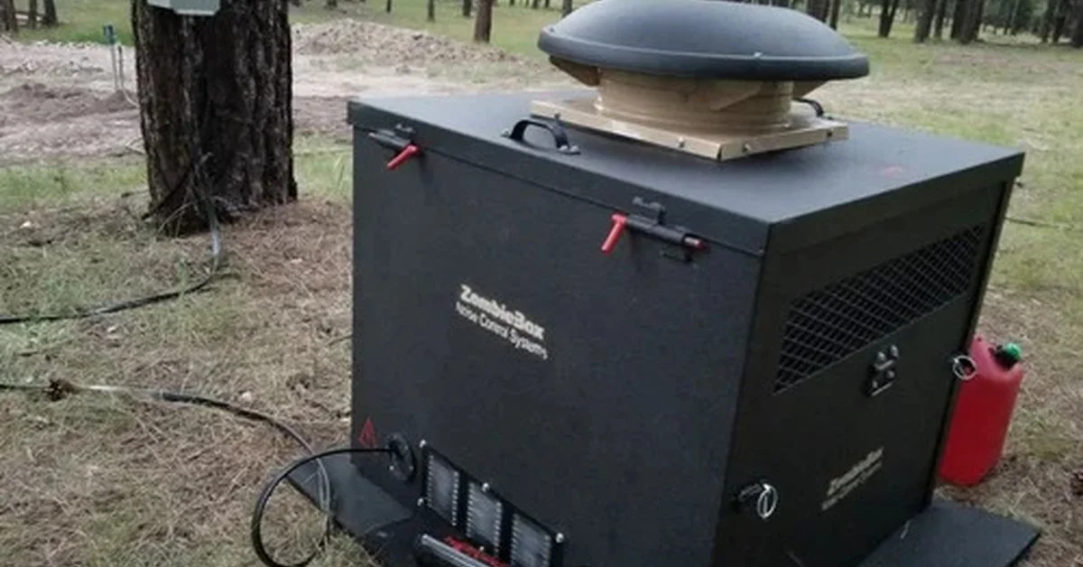 A black generator enclosure sits on a square pad among tall pine trees, with cables and a red fuel can nearby.