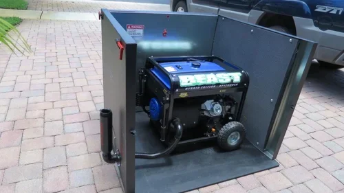 A portable generator sitting inside a gray metal enclosure on a paved driveway beside a parked pickup truck.