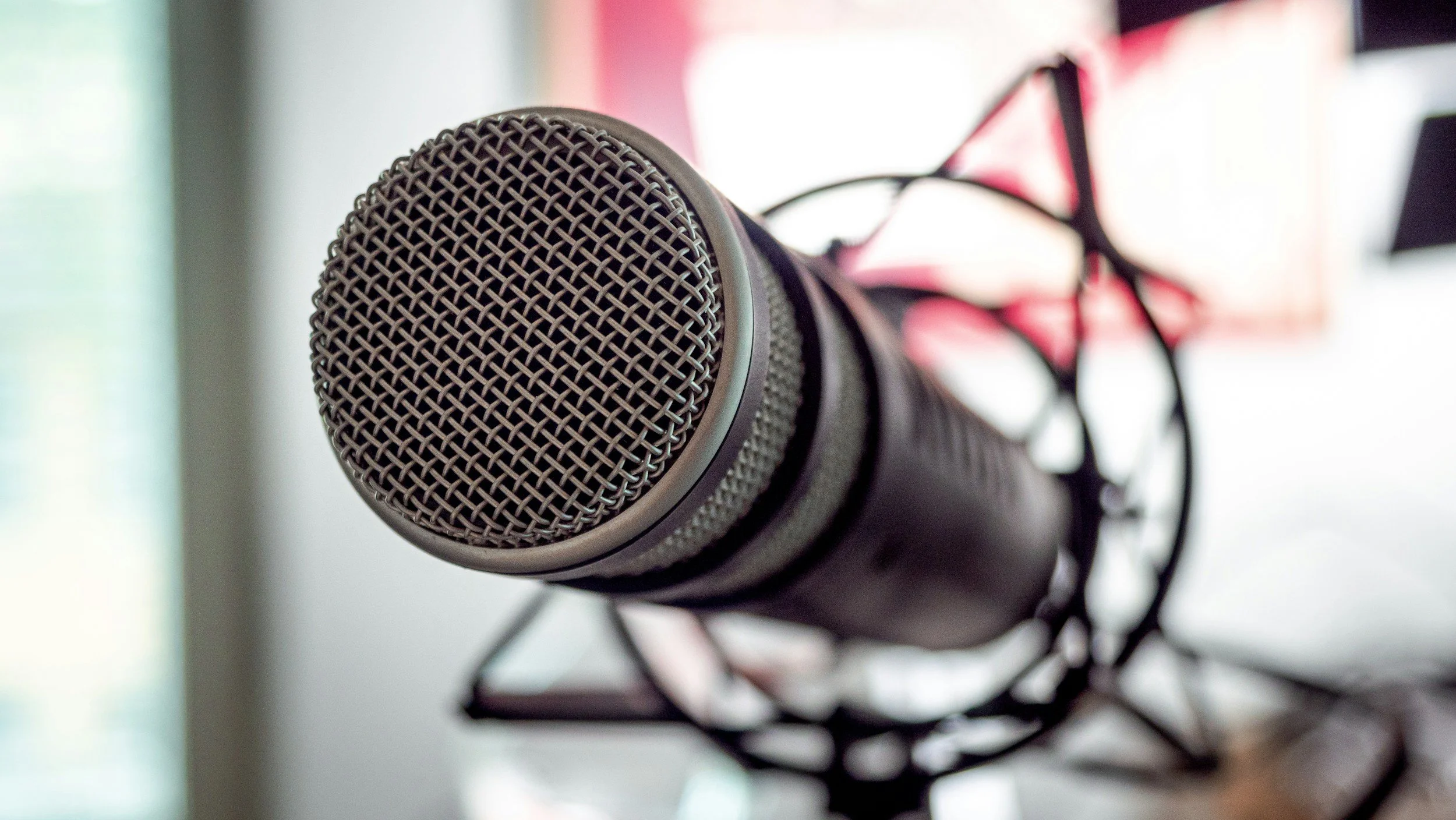 Close-up of a professional microphone mounted on a stand, with a blurred background.