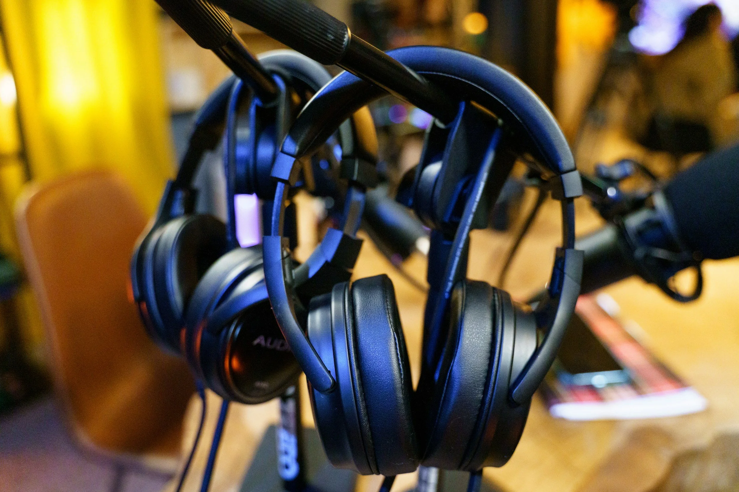 A row of black over-ear headphones hanging on hooks in a store or display area, with a blurred background.