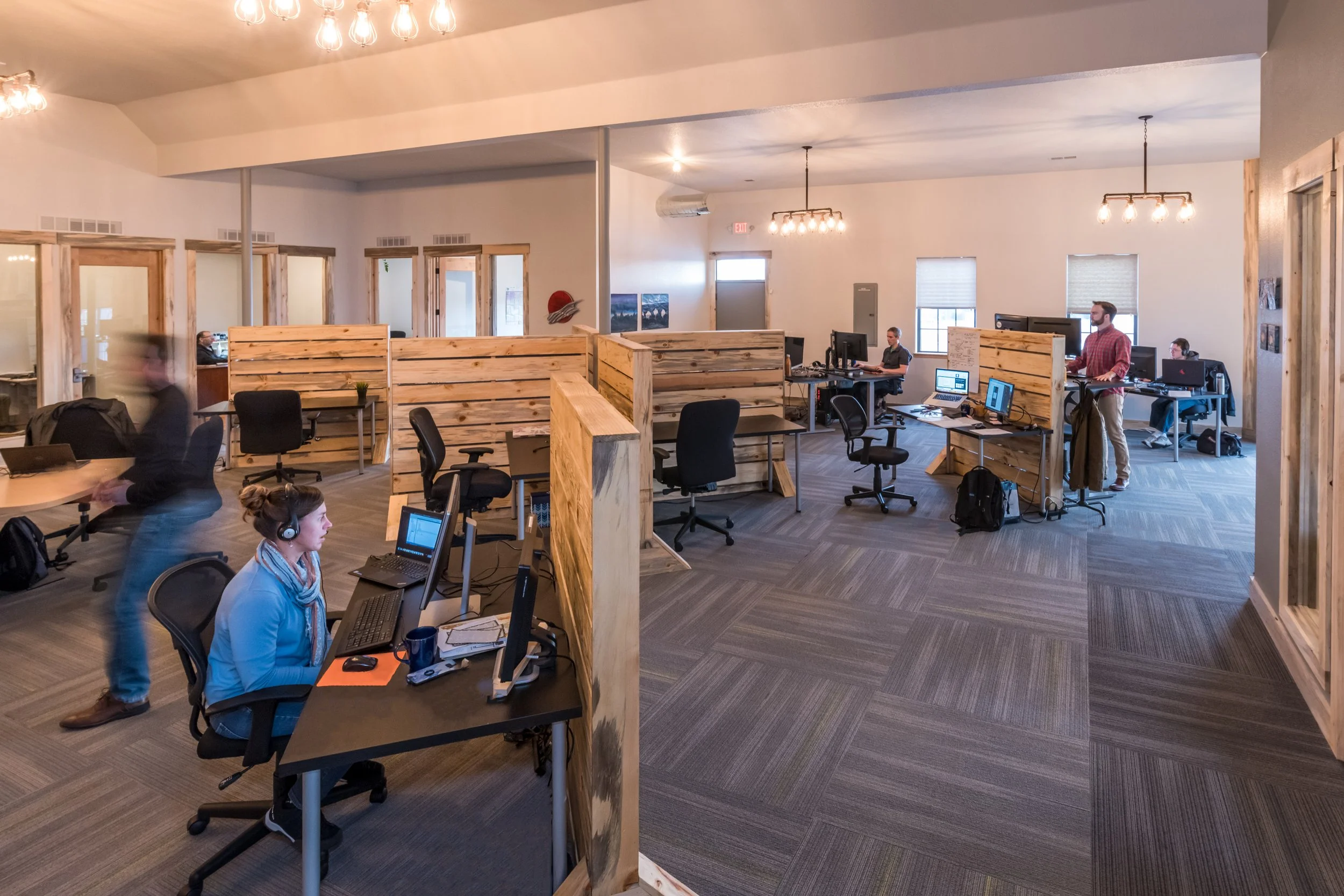 Coworking open office with wooden desk dividers and people working at computers.