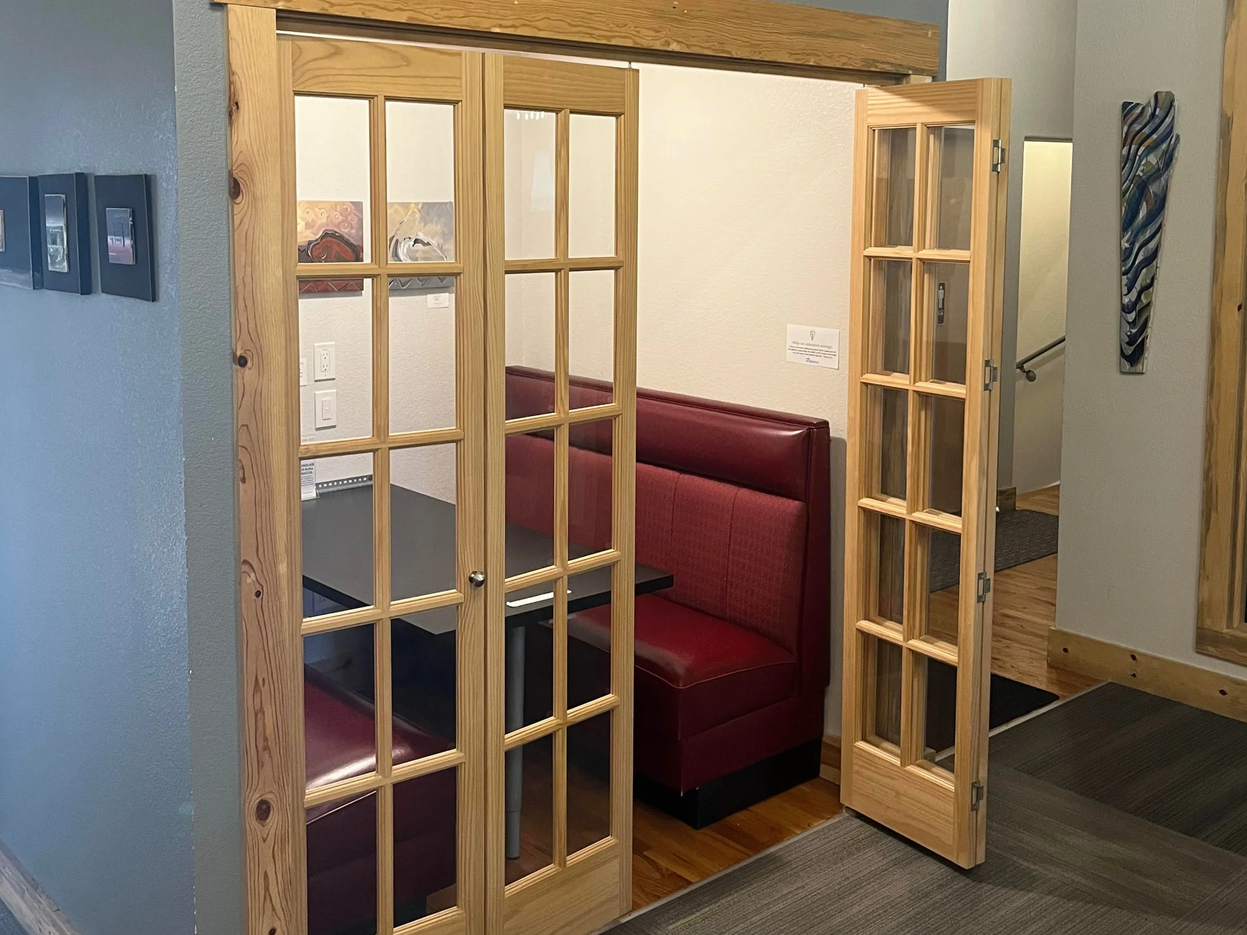 Private booth with red seating and glass doors in coworking space.