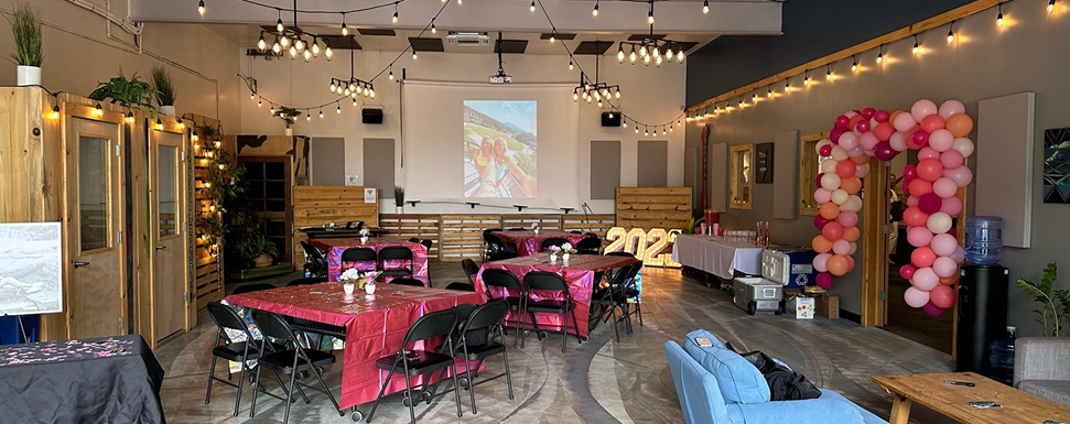 Decorated event space with tables, string lights, and balloon arch.