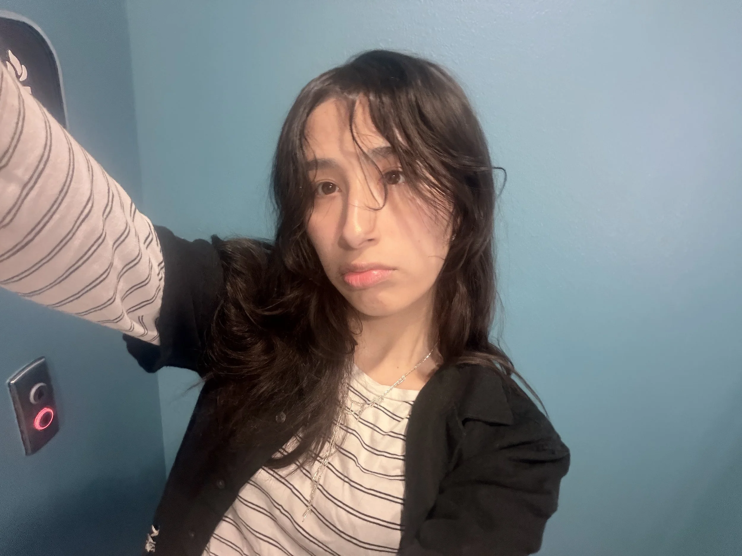 Selfie of Argent Martinez in striped long sleeve shirt in front of a blue wall.