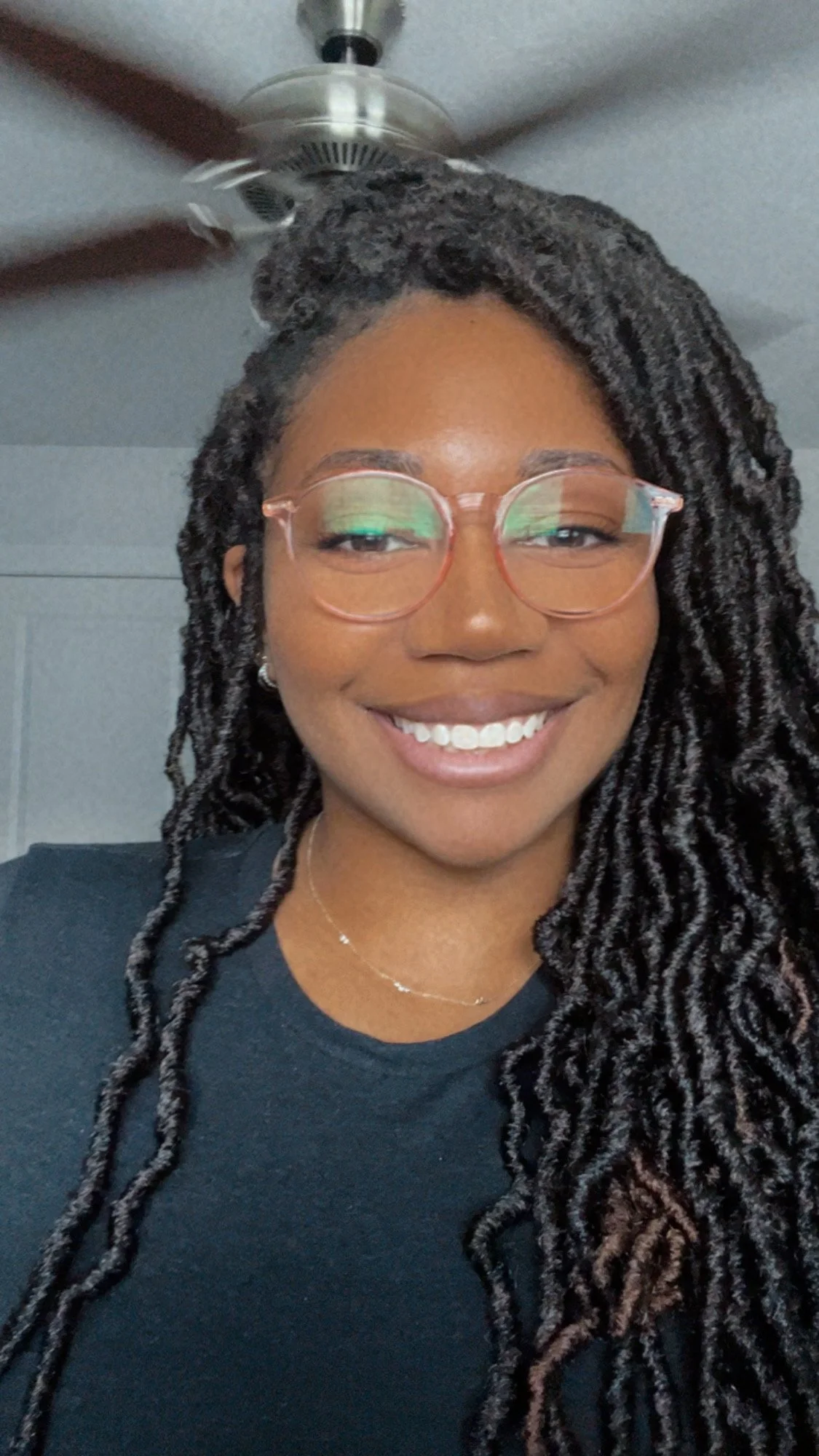 Headshot of Bri Martin, from the shoulders up, wearing glasses and smiling directly at camera.