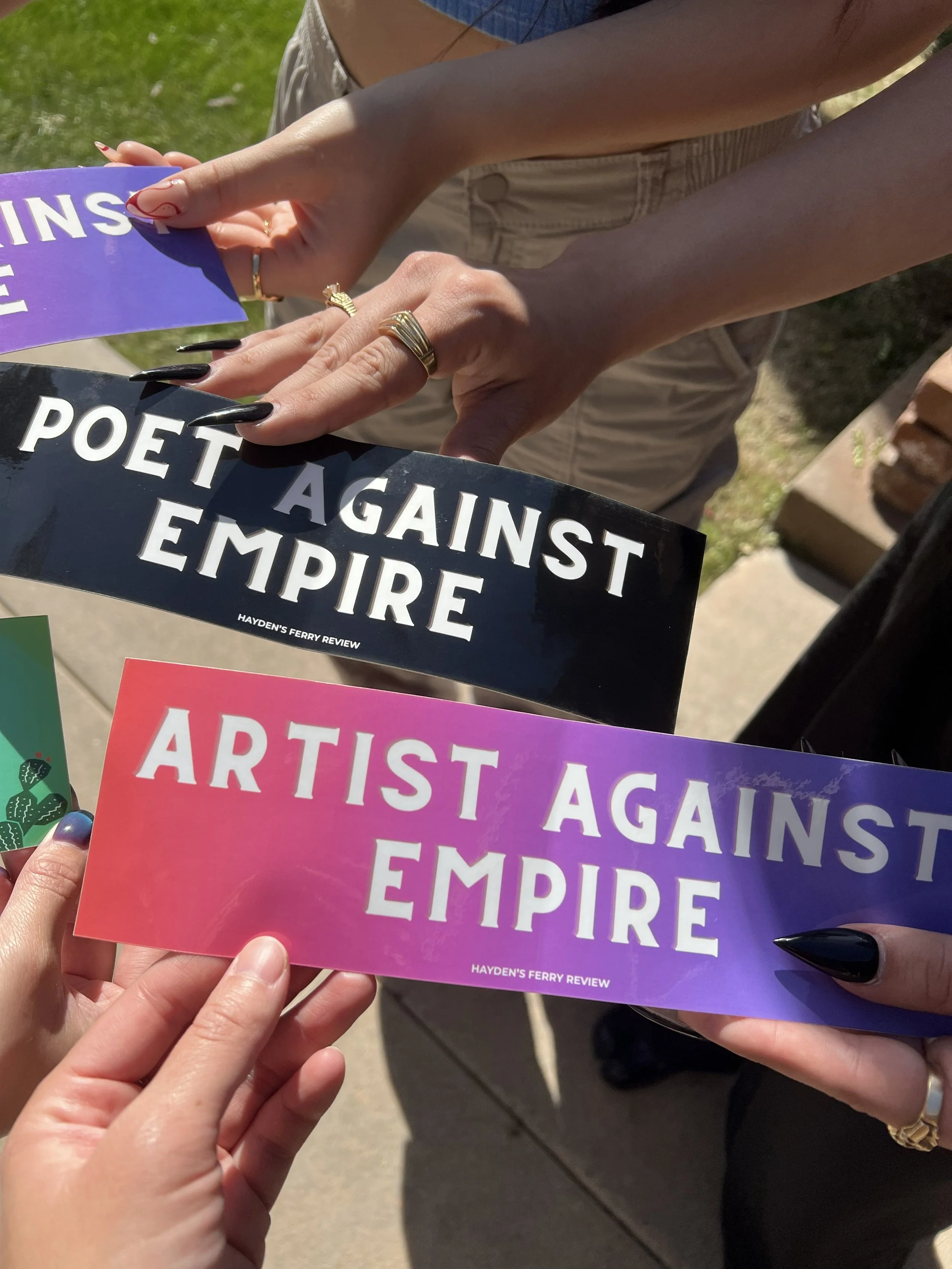 Hands hold bumper stickers against sidewalk background