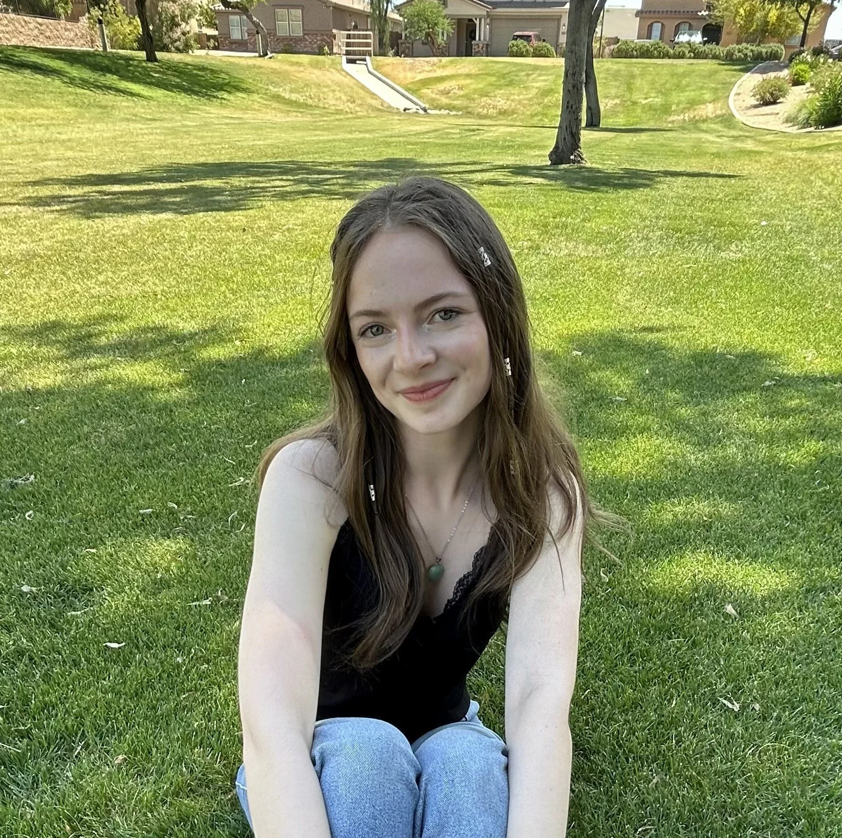 Kylee sits on grass and smiles at camera