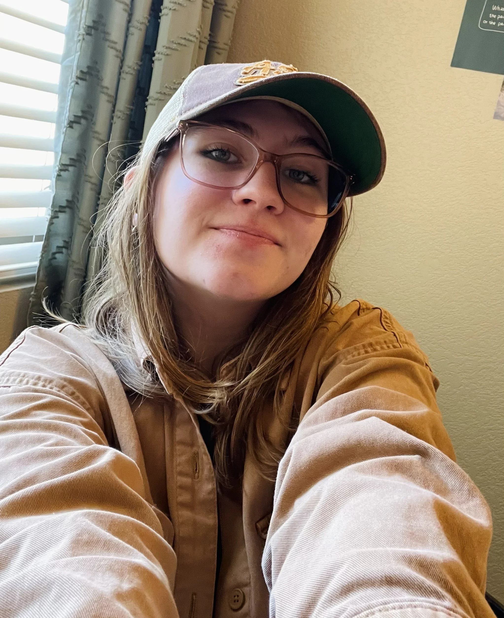 Selfie of Paige wearing a baseball hat, glasses, and jacket