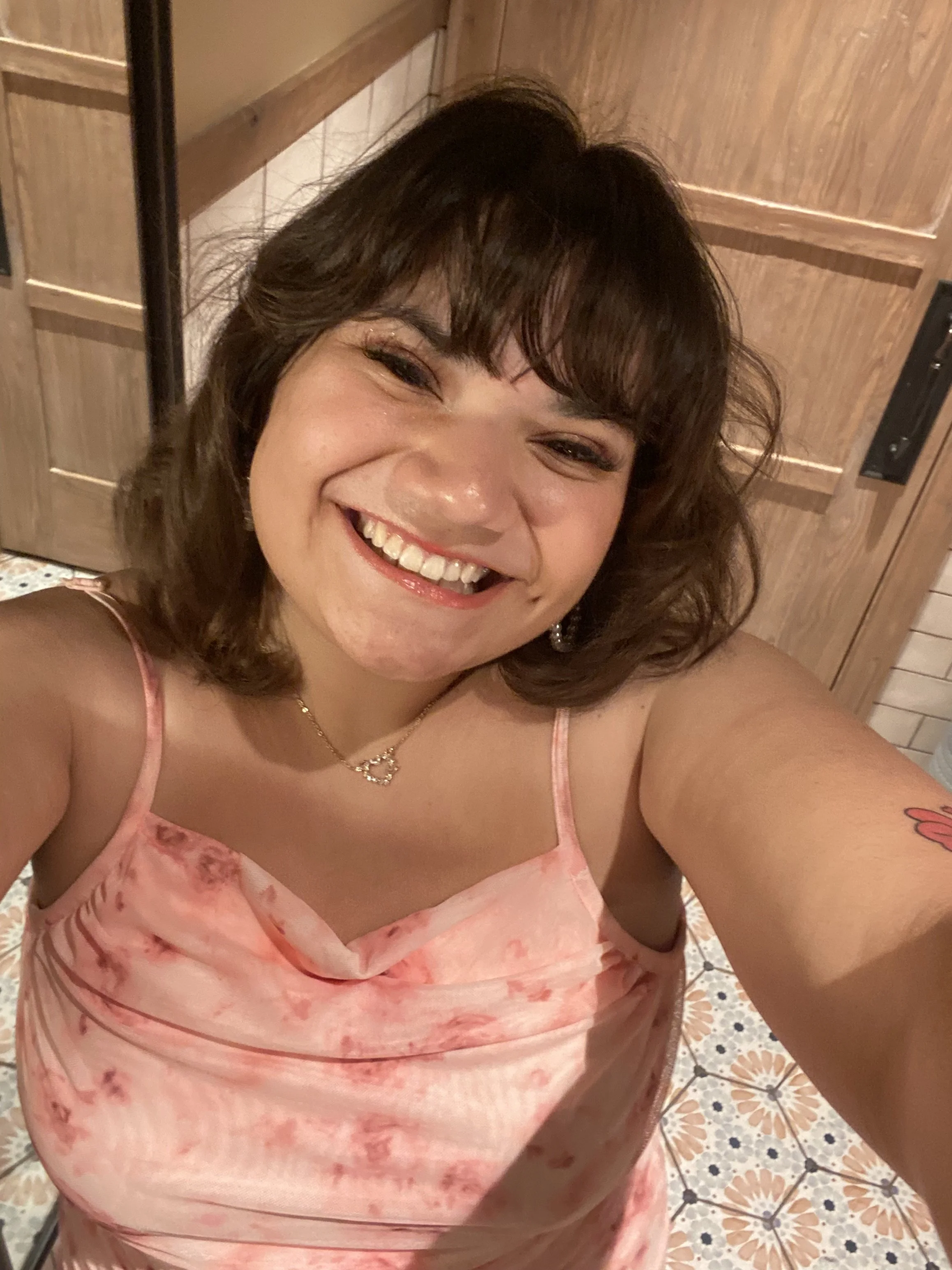 Selfie of Clem Marquez in a pink top, smiling at the camera.