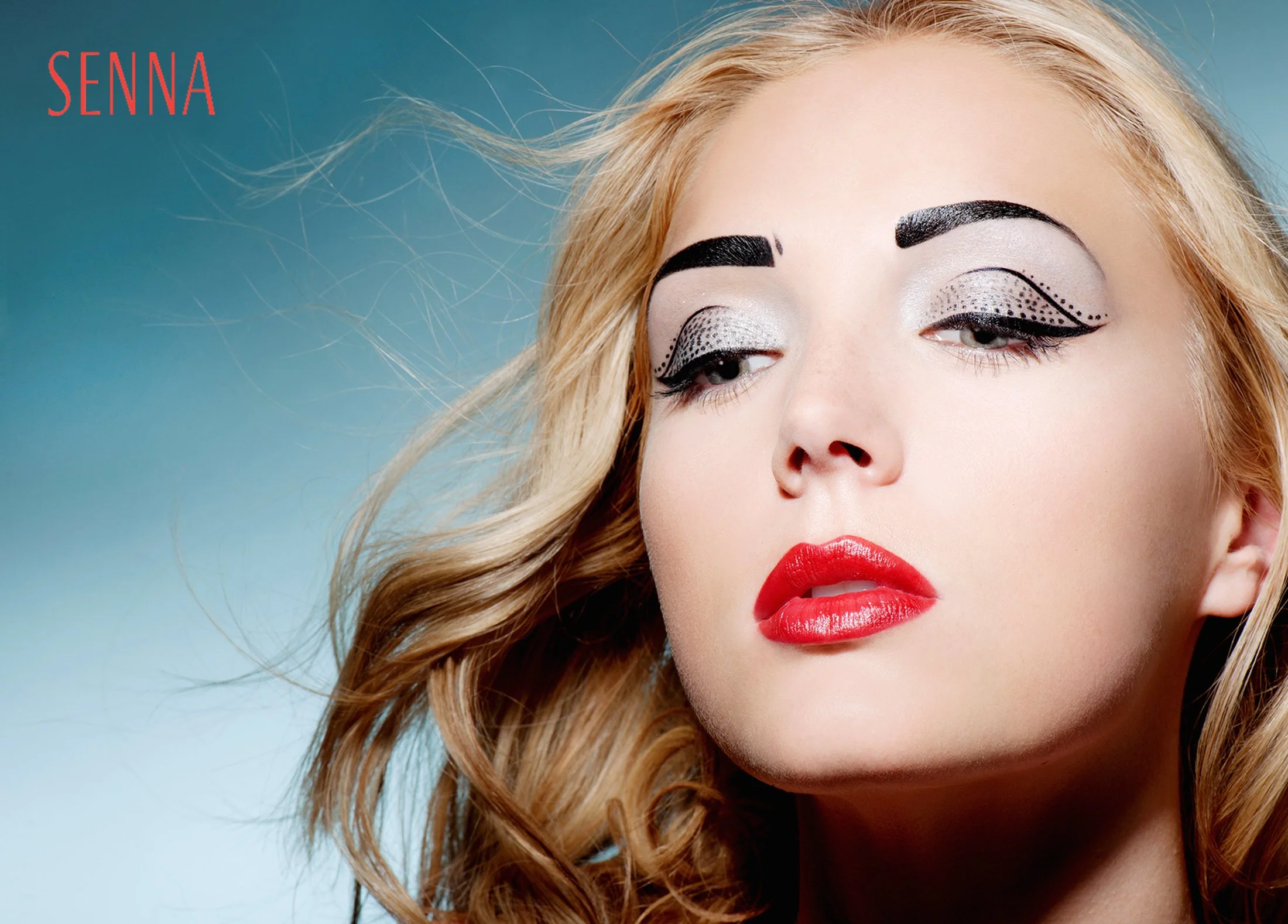 Close-up of a woman with blonde wavy hair and bold makeup, including red lipstick, black winged eyeliner, and dotted silver eyeshadow, with the word 'Senna' in red text in the top left corner.