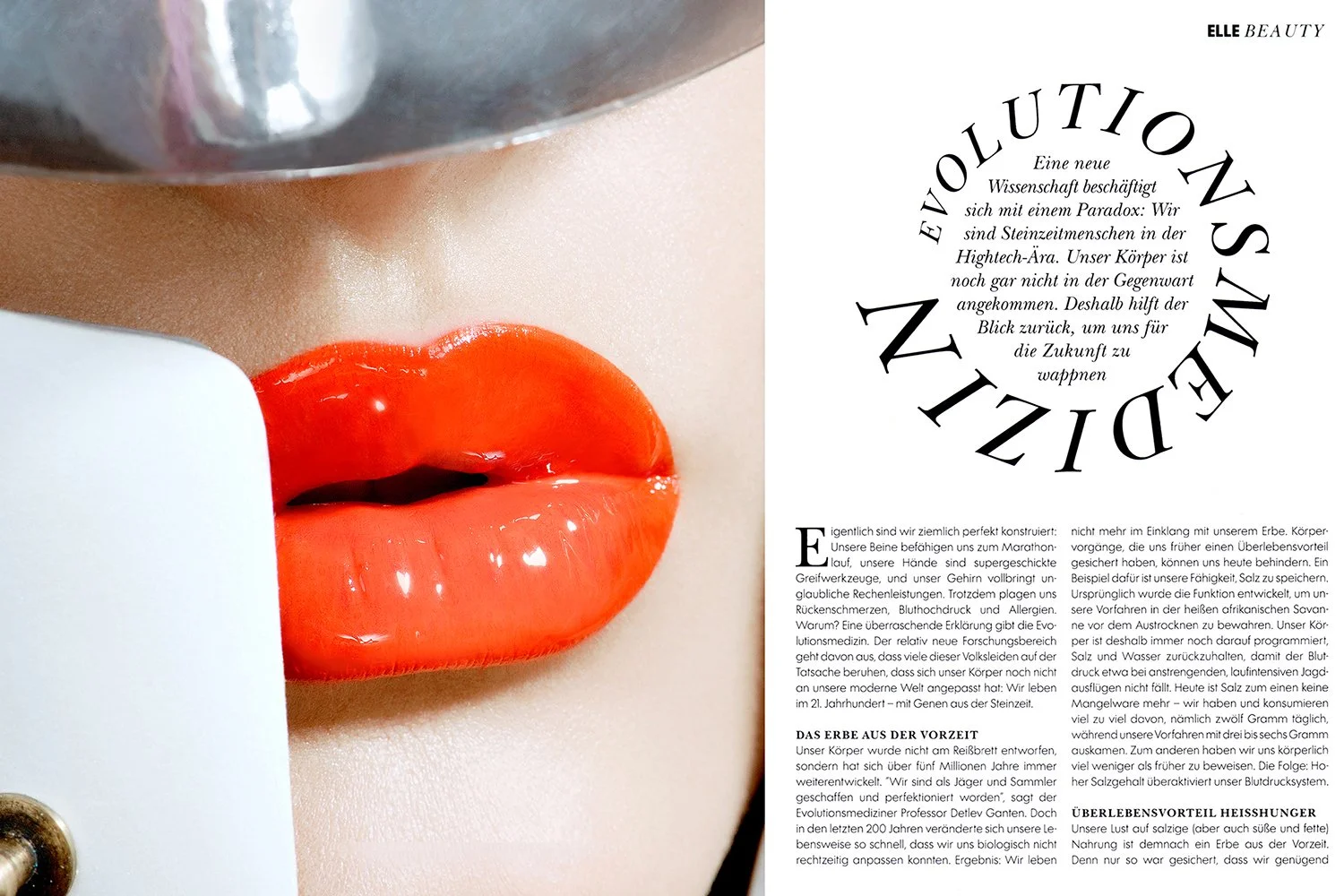 Close-up of glossy lips with orange lipstick and and parts of a helmet, with a magazine page from german ELLE on the right showing text about evolution and science.