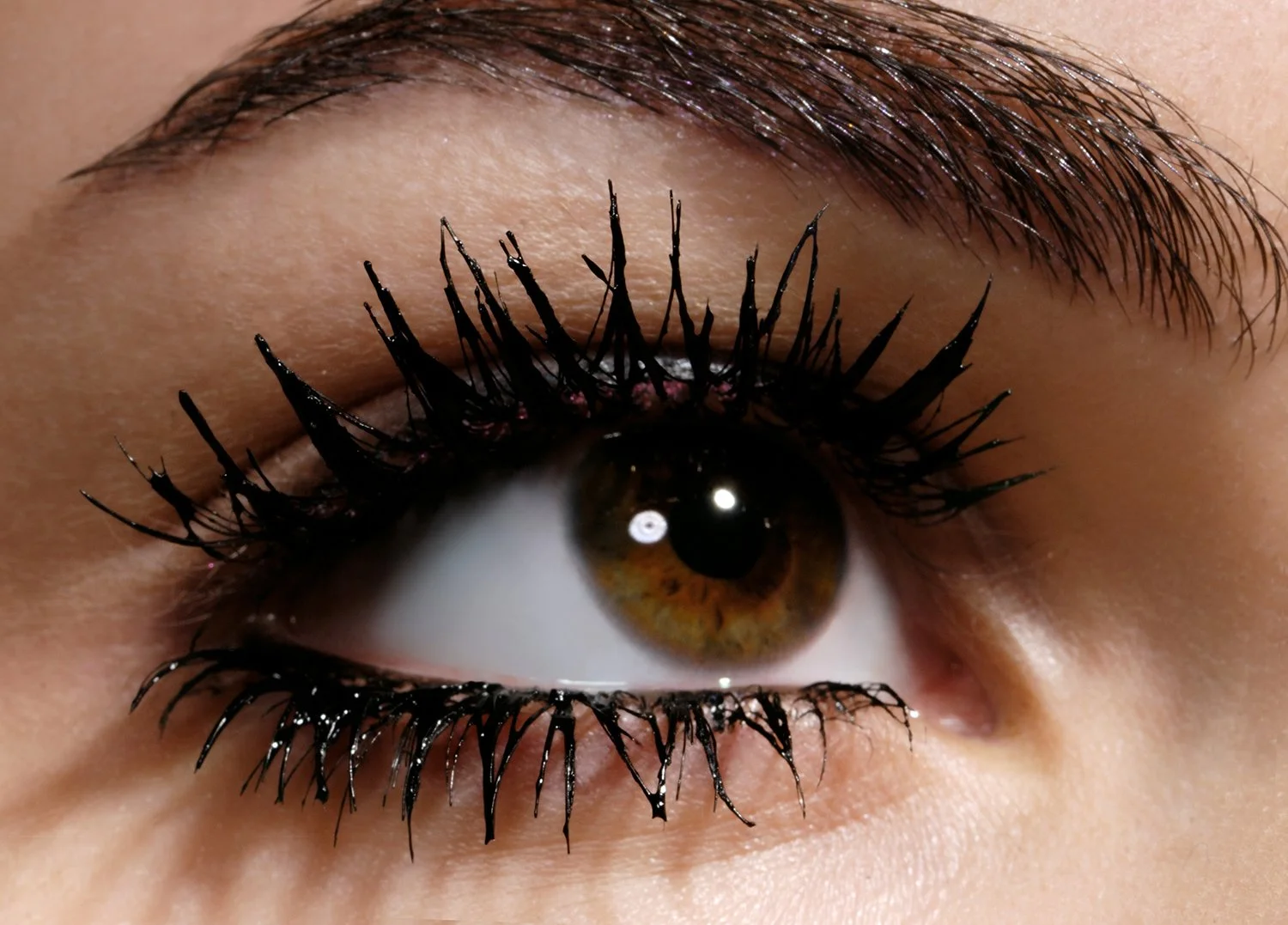 High-definition macro eye photography by beauty photographer Daniella Hehmann, capturing intricate mascara detail, groomed brows, and natural dewy skin texture under soft, diffused beauty lighting. L.A. & Munich based.