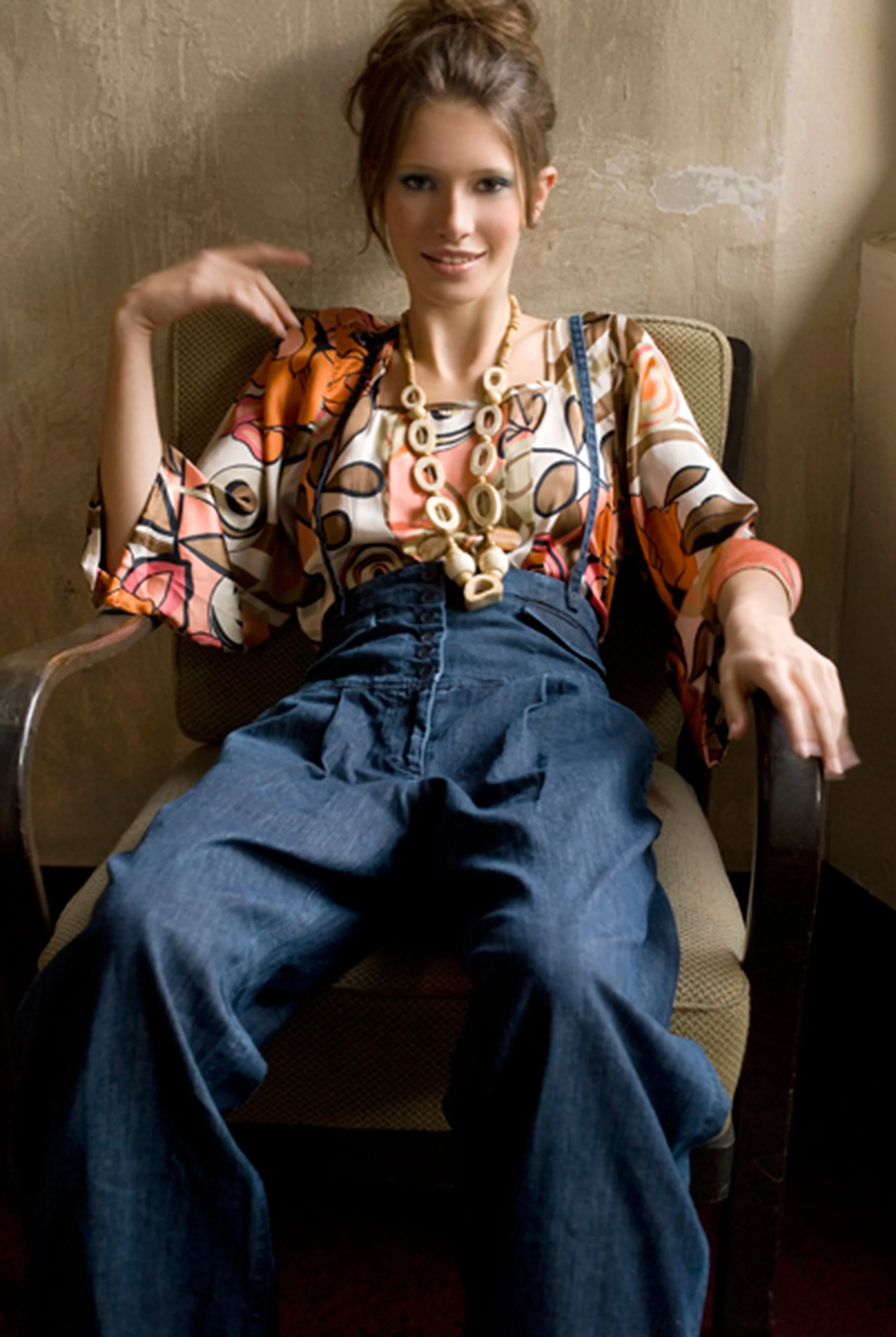 Studio fashion portrait by Daniella Hehmann Photography shot in Munich featuring a model in high-waisted wide-leg denim trousers and a graphic patterned blouse with oversized statement jewelry.