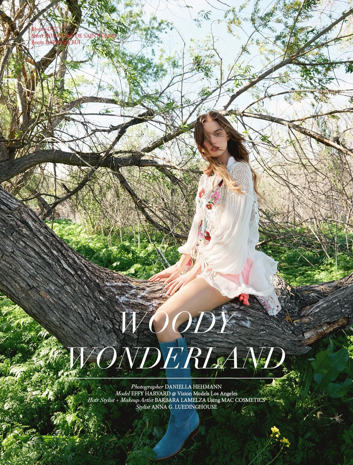 A woman with long hair sitting on a tree branch in a lush green outdoor setting with trees and foliage, wearing a light-colored dress and blue boots, with sunlight filtering through the trees.