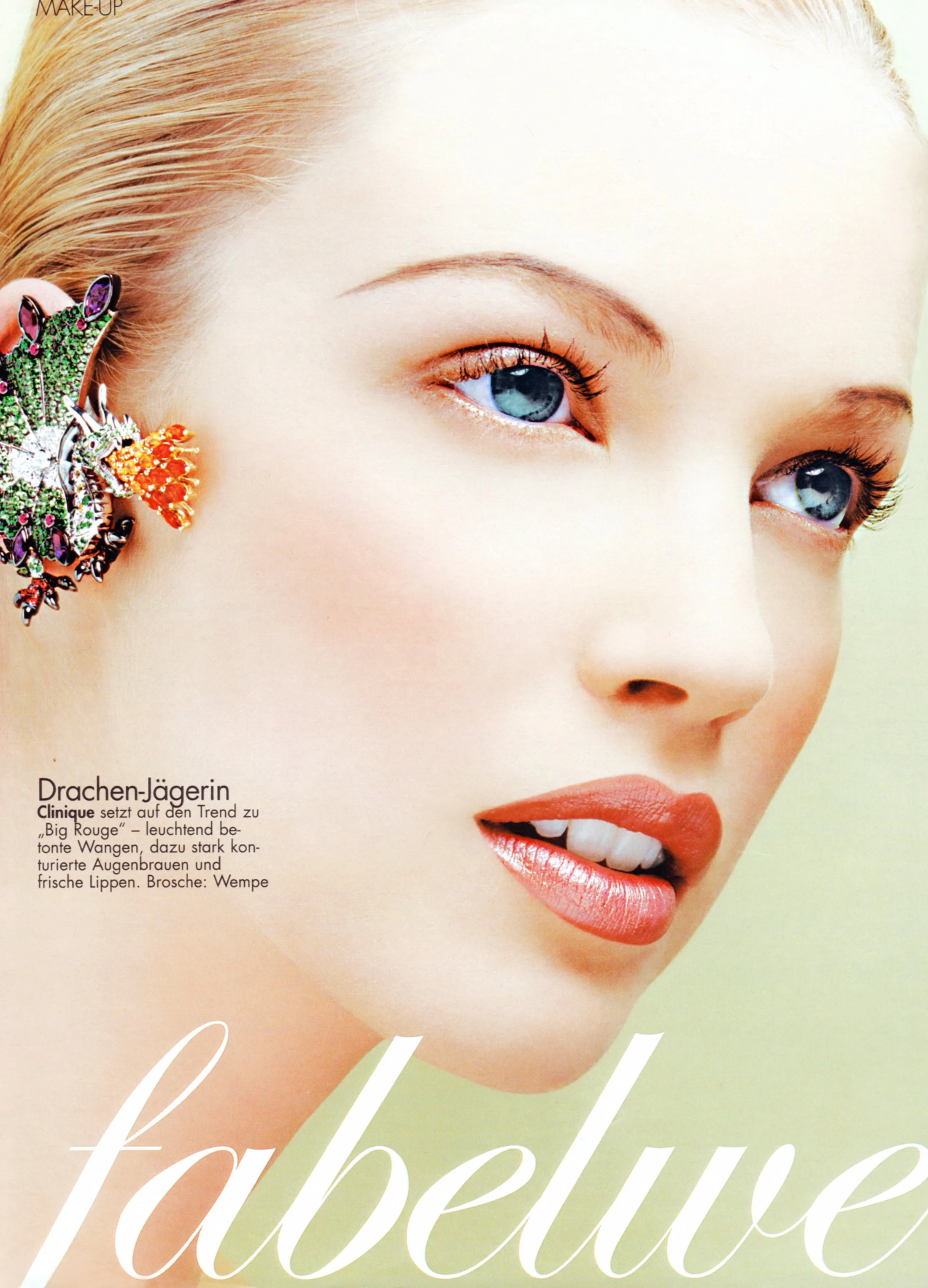 Editorial beauty shot for German Cosmopolitan by Daniella Hehmann, featuring a striking green butterfly accessory over the lips. Skin is rendered with a velvet finish under bright, clean studio lighting. Shot in Los Angeles.