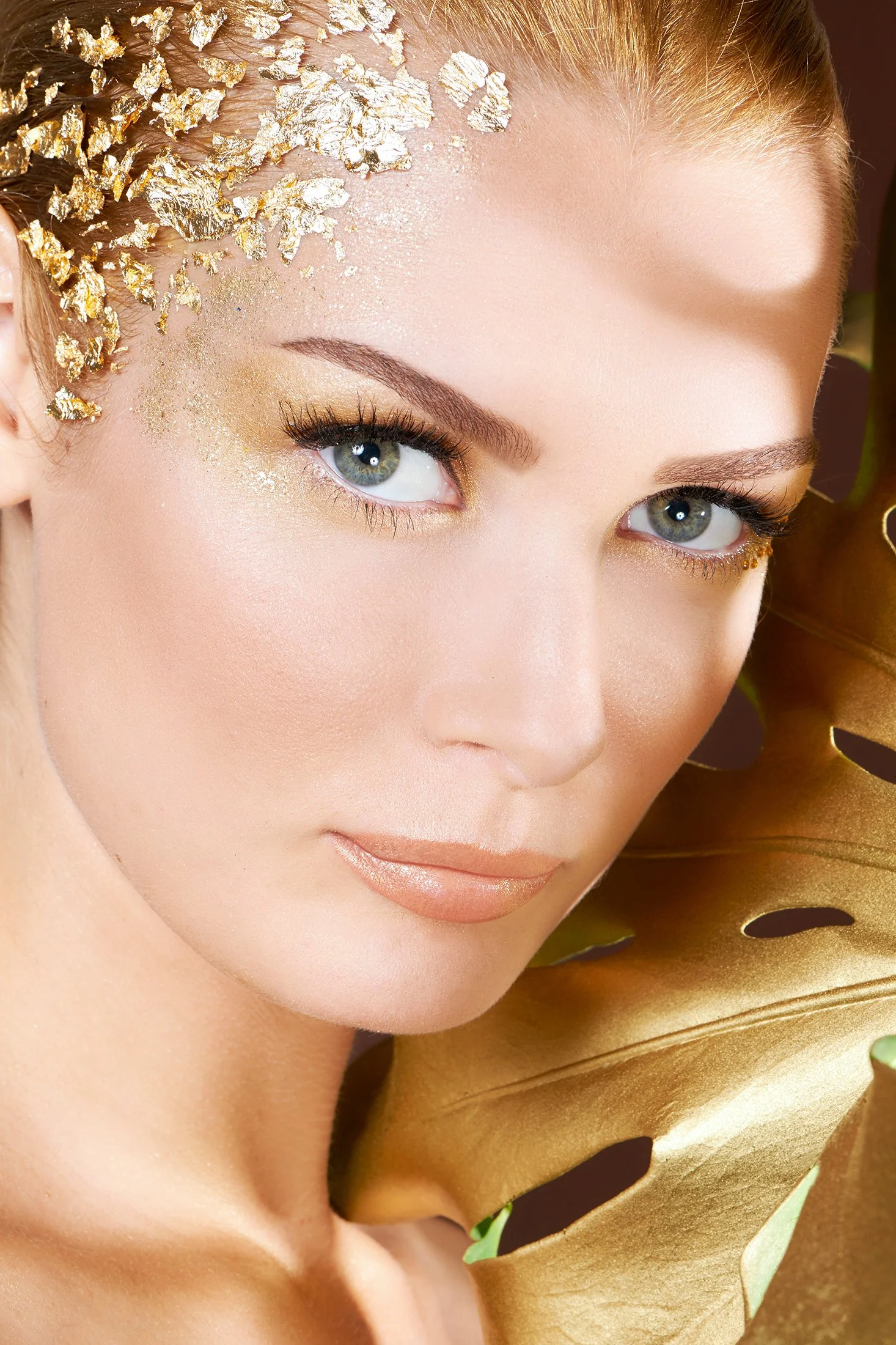 Commercial cosmetic advertising for Senna Cosmetics by Los Angeles beauty photographer Daniella Hehmann. Makeup by Eugenia Weston features an avant-garde "Golden Eye" look with shimmering gold eyeshadow and metallic gold leaf applied to the temple. T