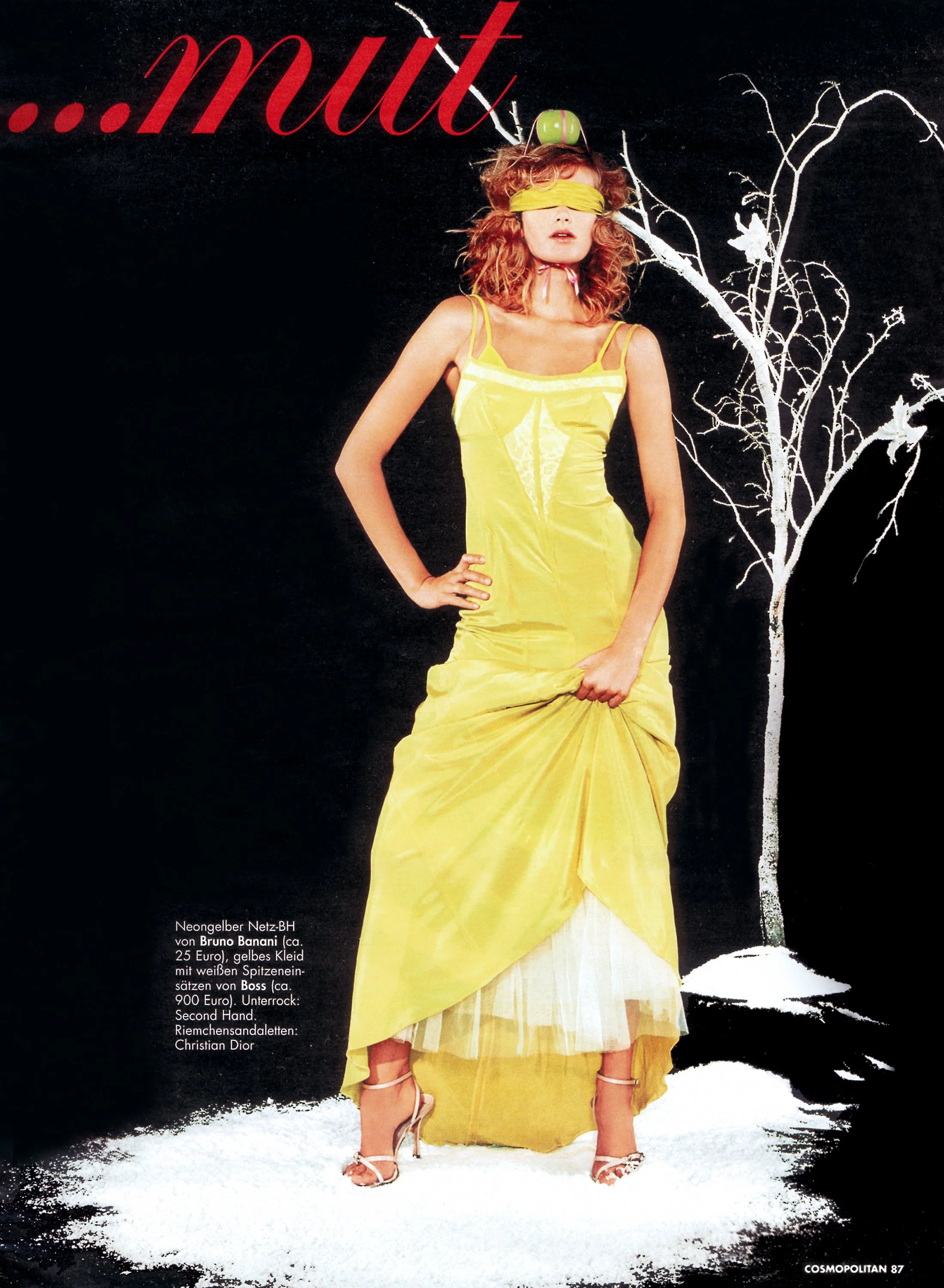 A high-concept fashion editorial shot for German Cosmopolitan by photographer Daniella Hehmann featuring a model in a vibrant yellow floor-length gown posed against a dramatic black backdrop with white graphic tree illustrations.