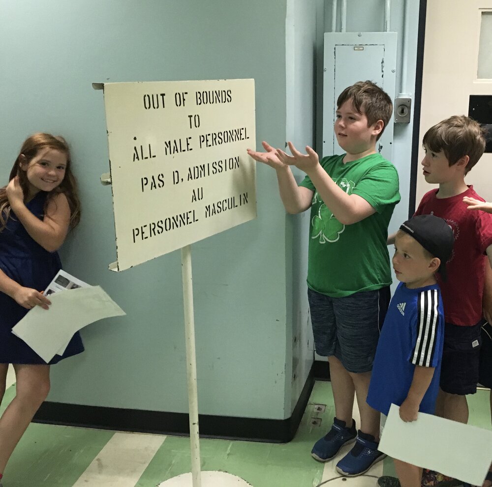 kids at the diefenbunker by a sign that says “out of bounds to all male personnel”