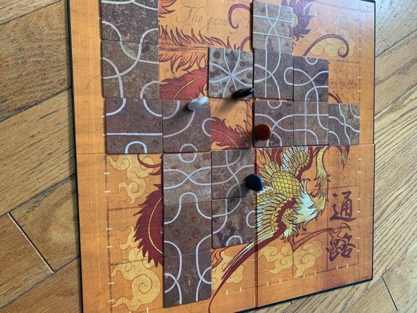 Tsuro game board with tiles and game pieces on the board to show how pieces move during the game