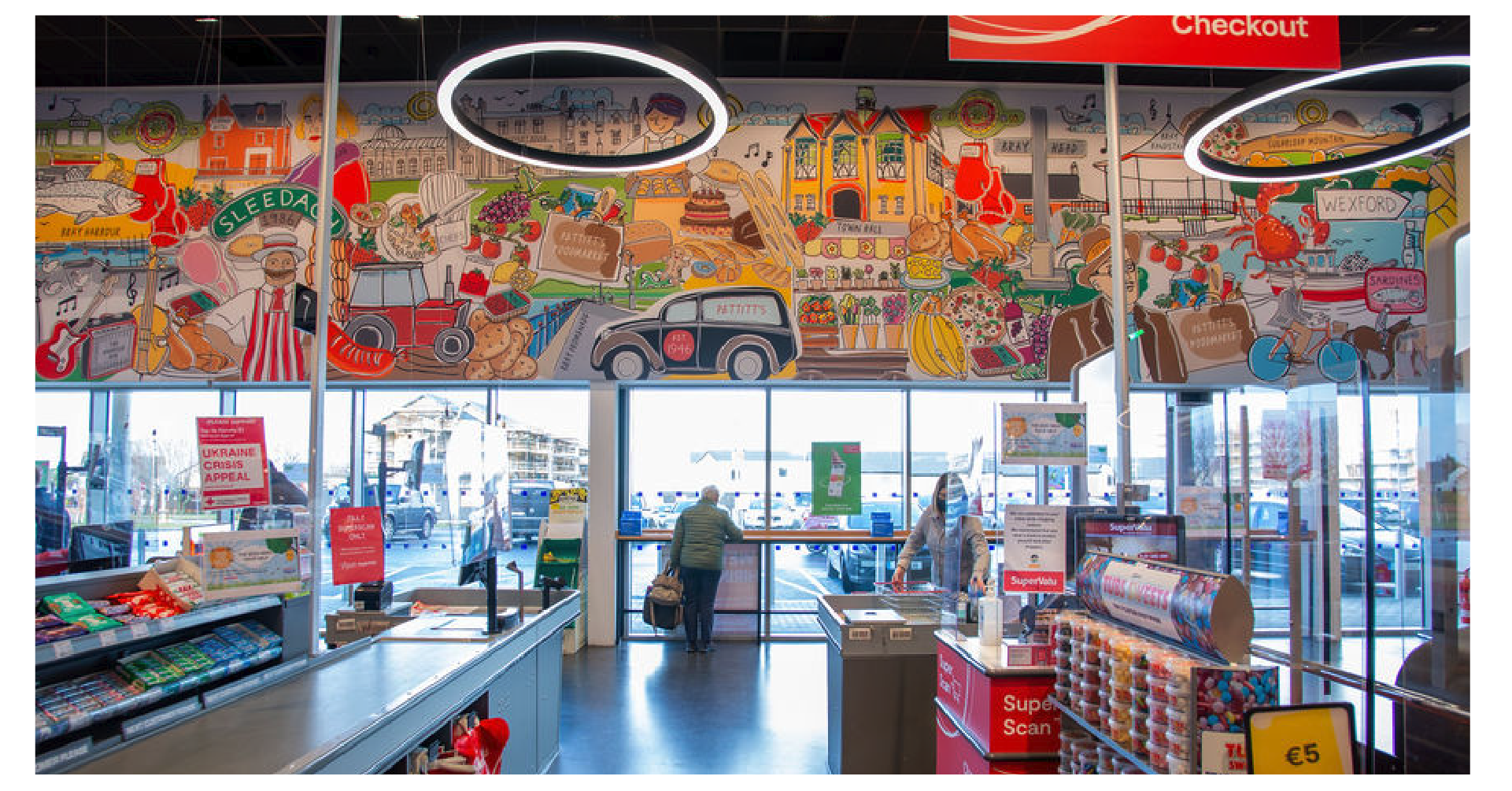 Vibrant hand-drawn illustration celebrating Pettitt’s Foodmarket and Wexford, featuring local produce, bakery items, seafood, farming, flowers, landmarks, and community scenes in a colourful mural-style composition.