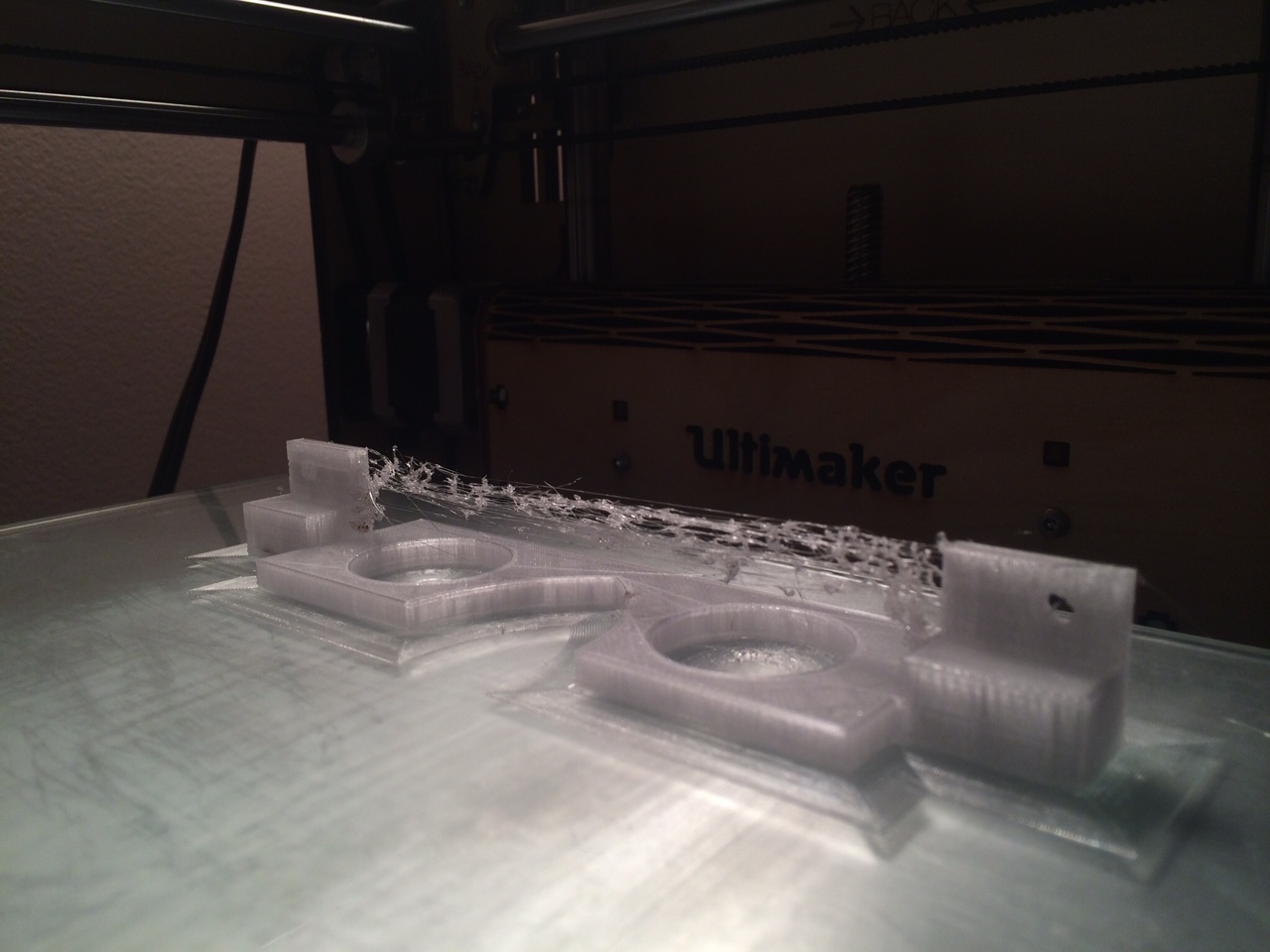 The lens holder after printing. The string in between the blocks is most likely due to the printer nozzle being too hot and allowing plastic to drip while traveling between the part. Although the print turned out fine, next time I will use a lower temperature for Amphora.