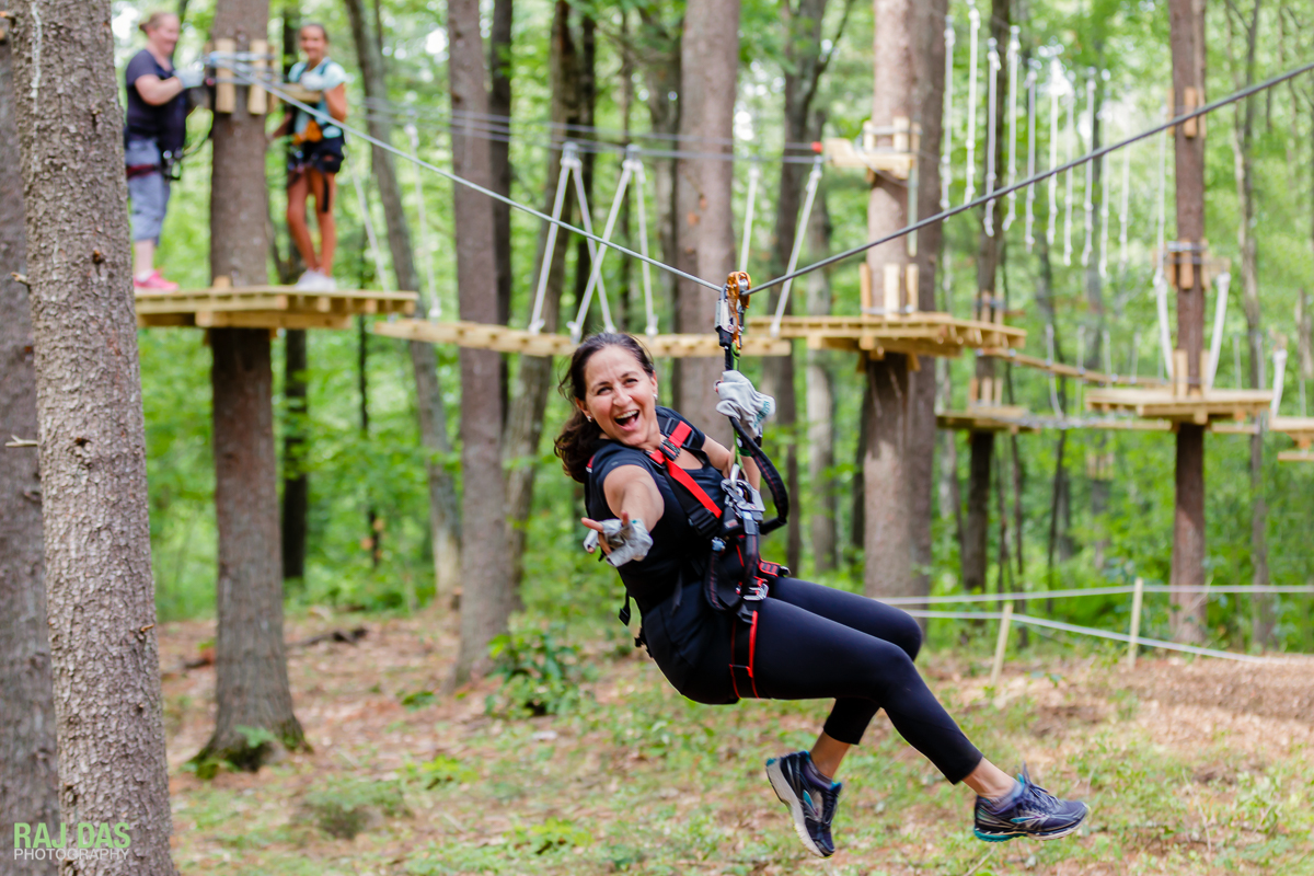 Original full image of an adult on a zip line that's on the left of the billboard