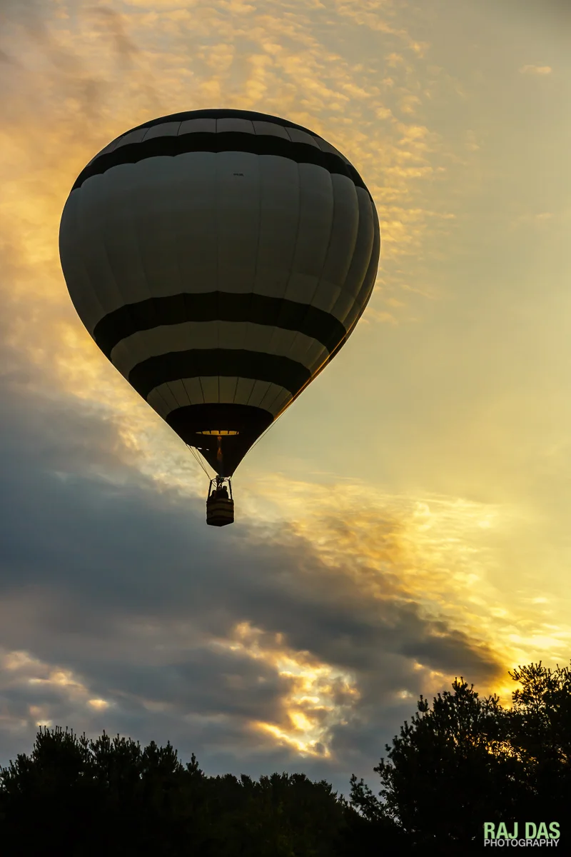 The first balloon ascends as the early rays of the morning sun kiss the sides