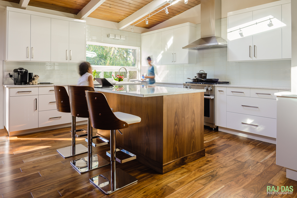 The whites of the cabinets and counter tops go very well with the brown and wood tones of the floor and ceiling in the newly renovated kitchen.