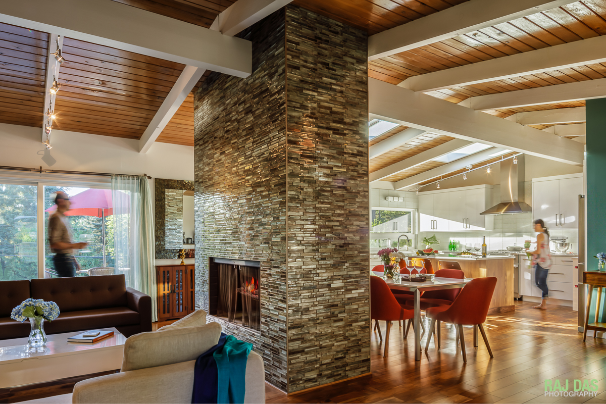 A view of the living space, dining and kitchen area and the outdoor front patio. The fireplace and center column separates the living from the dining space while preserving the flow and openness.