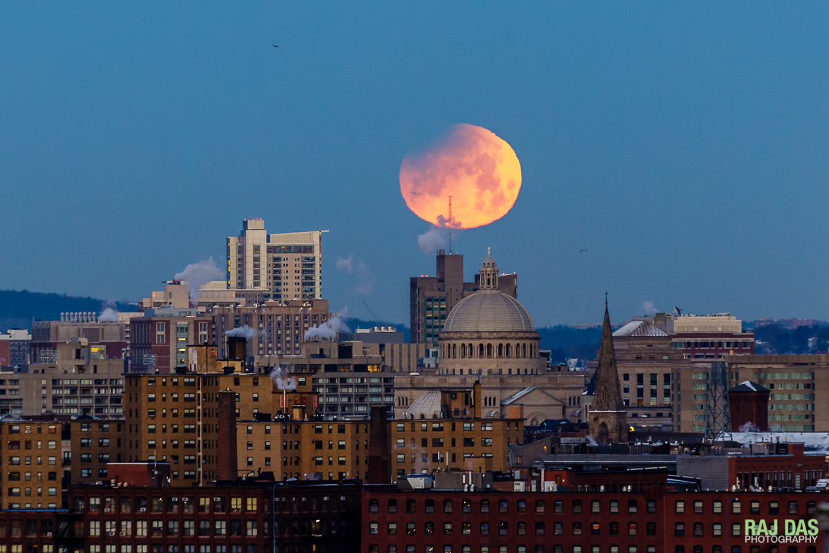 A close shot of the setting super blue blood moon with the Boston skyline and dome of the First Church of Christ, Scientist visible.