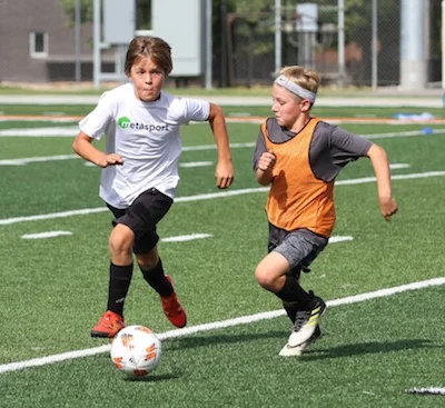 Two 9U-11U MetaSport soccer players battling for ball at training