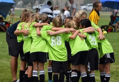 9U-11U MetaSport girls team huddles before kickoff.