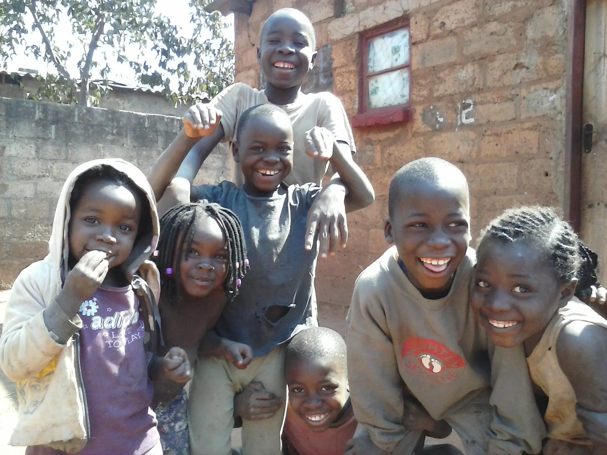 Children from the slum compound of Chainda within Lusaka, Zambia happily pose for a photo taken by Mulenga during a visit in August 2014.