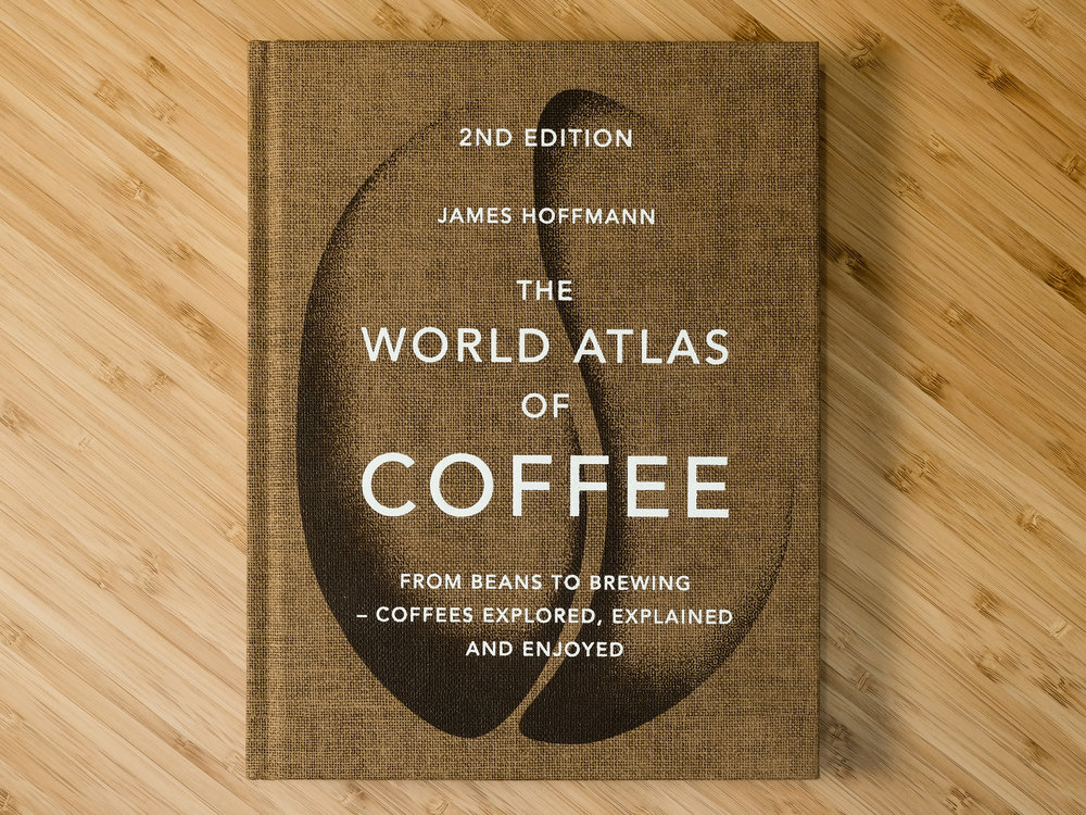 Front cover of "The World Atlas of Coffee" on a wooden table