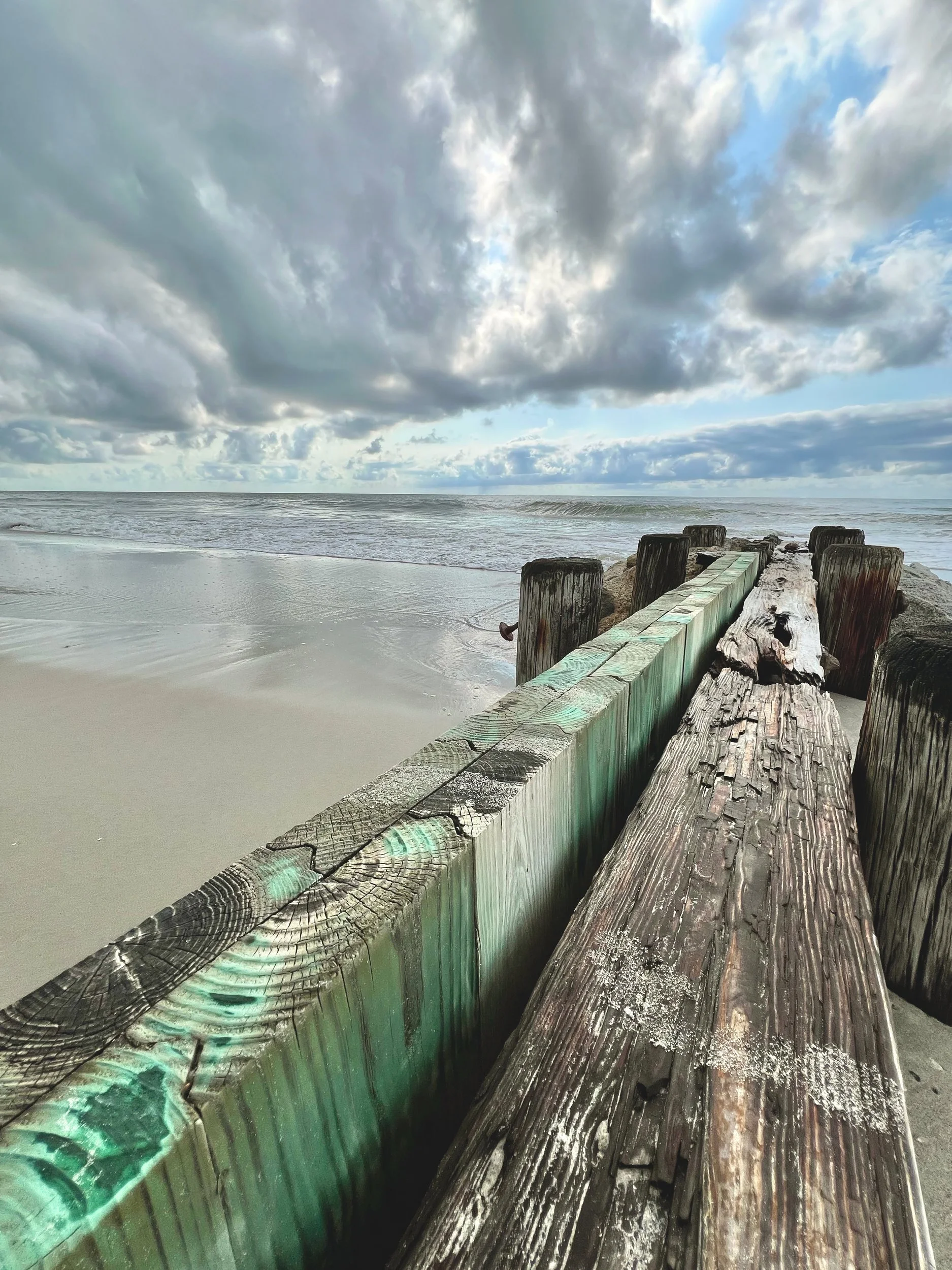 Weathered wooden jetty with peeling sea-green paint running into the ocean