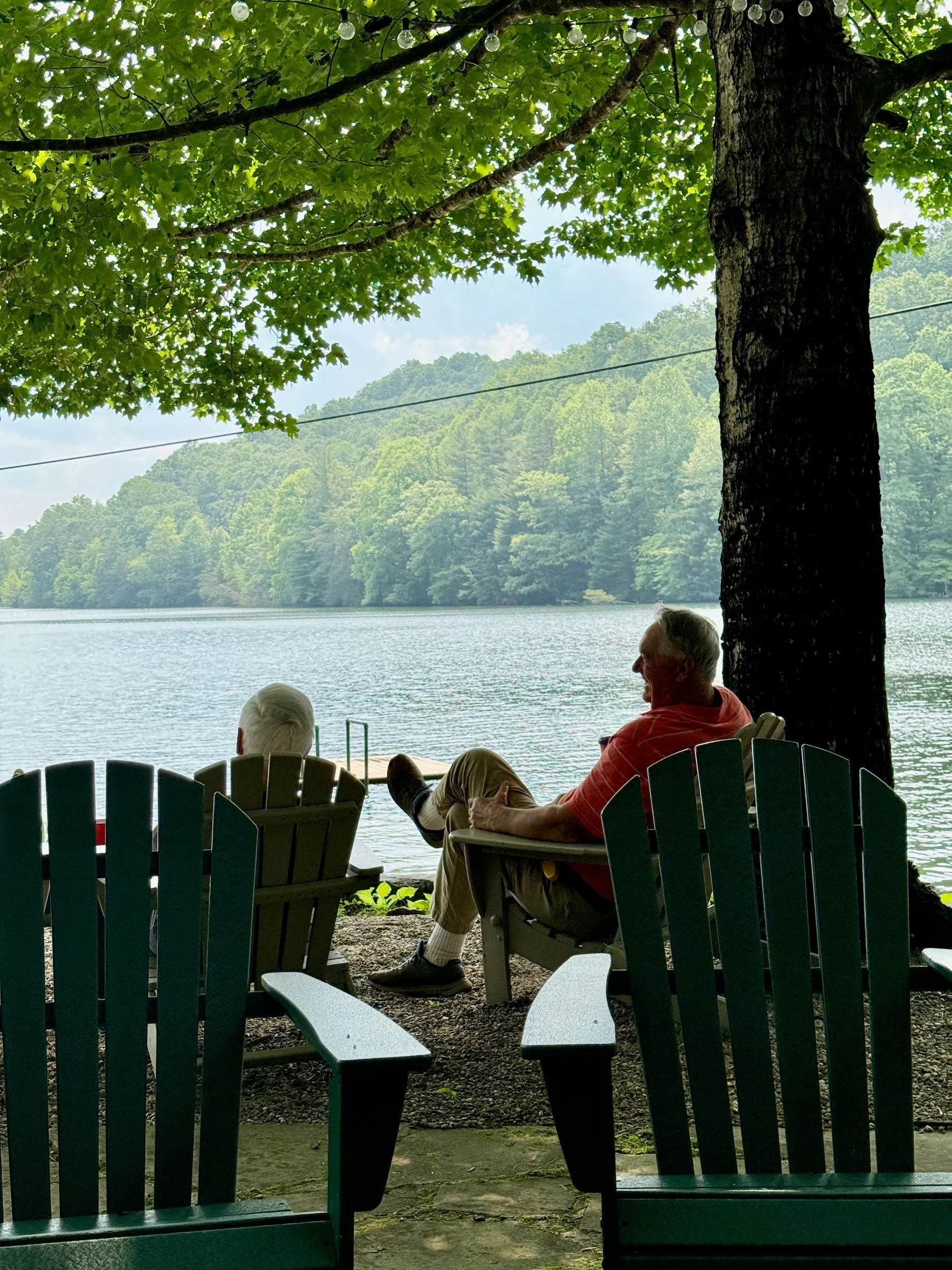 Two people in Adirondack chairs looking out at Lake Summit