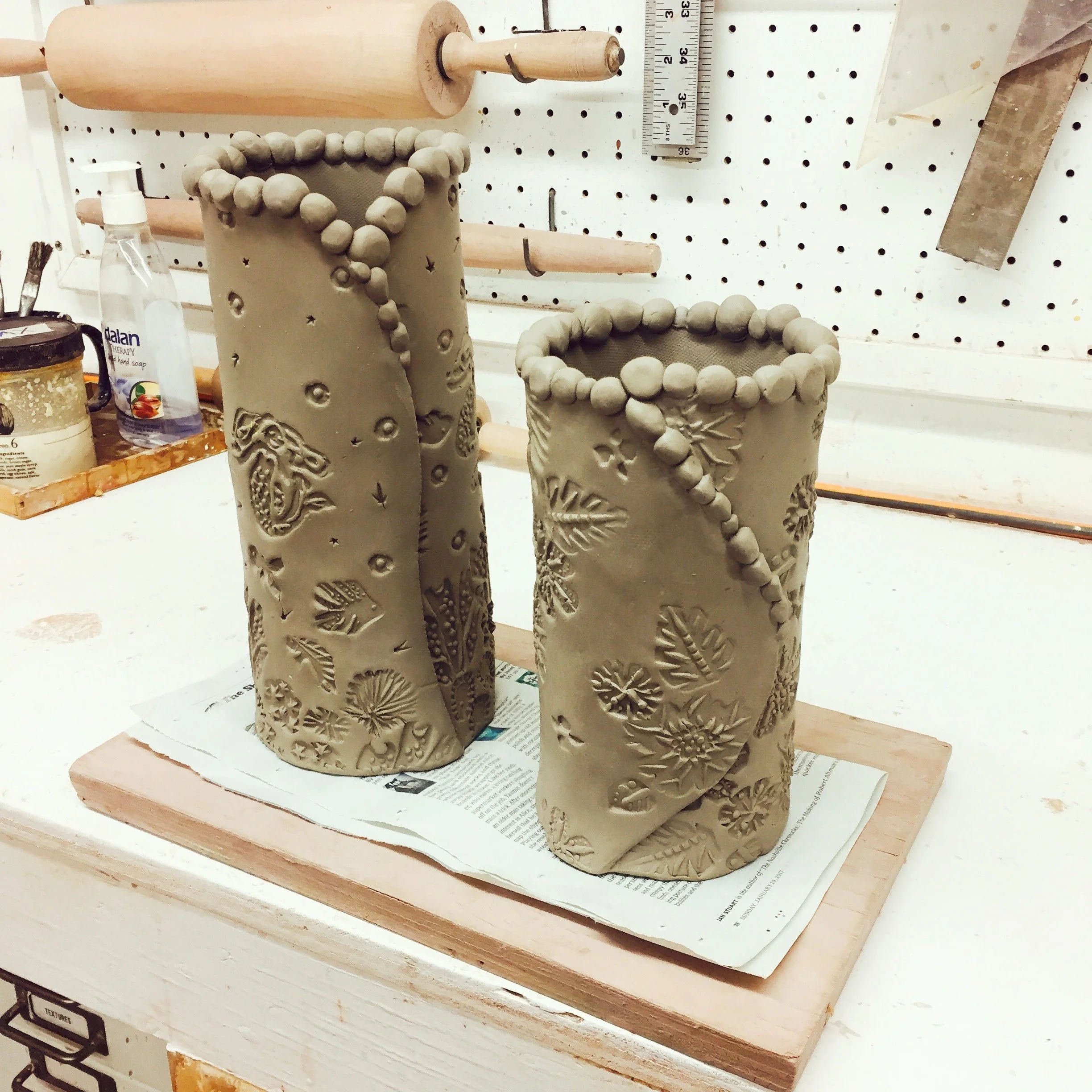 Textured vases drying on the studio table, greenware