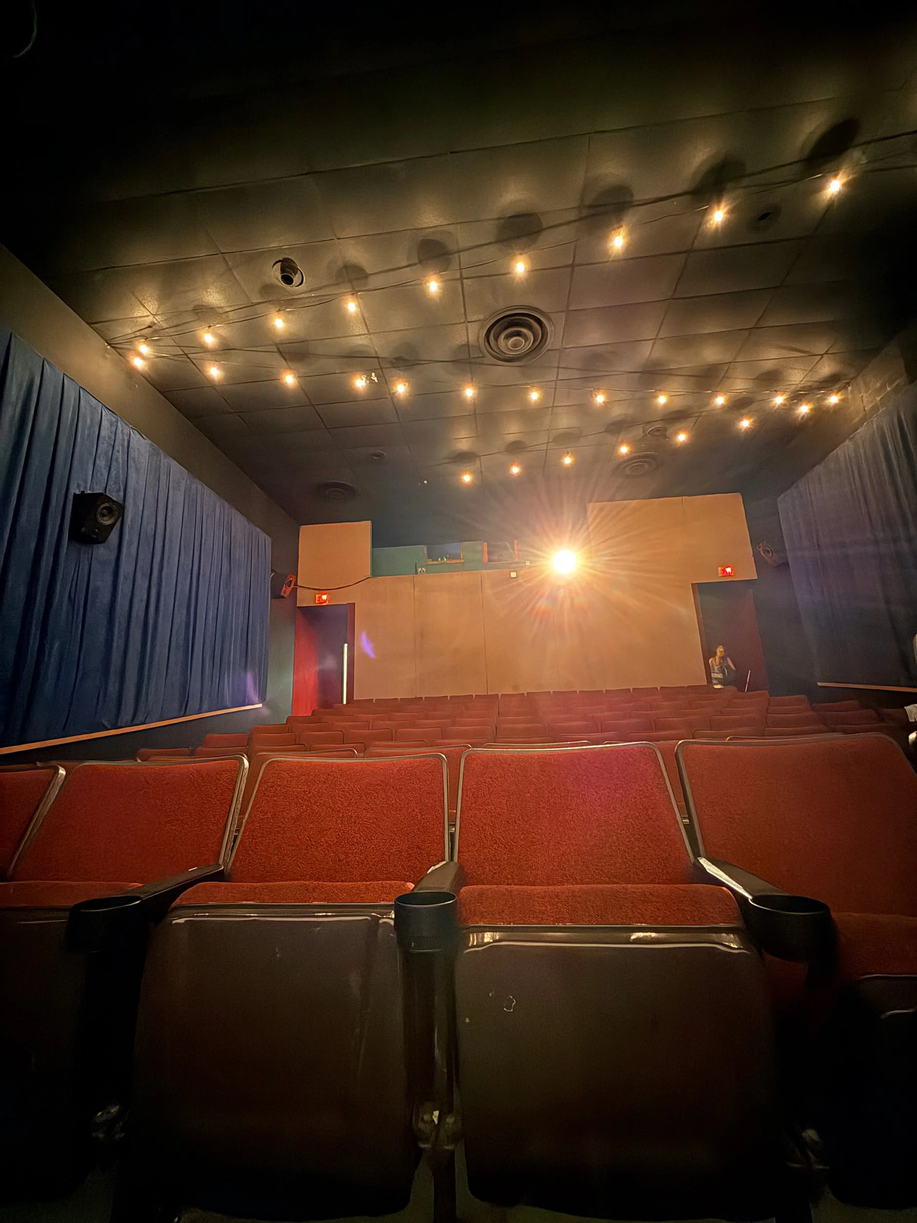 Empty theater with red seats under string lights