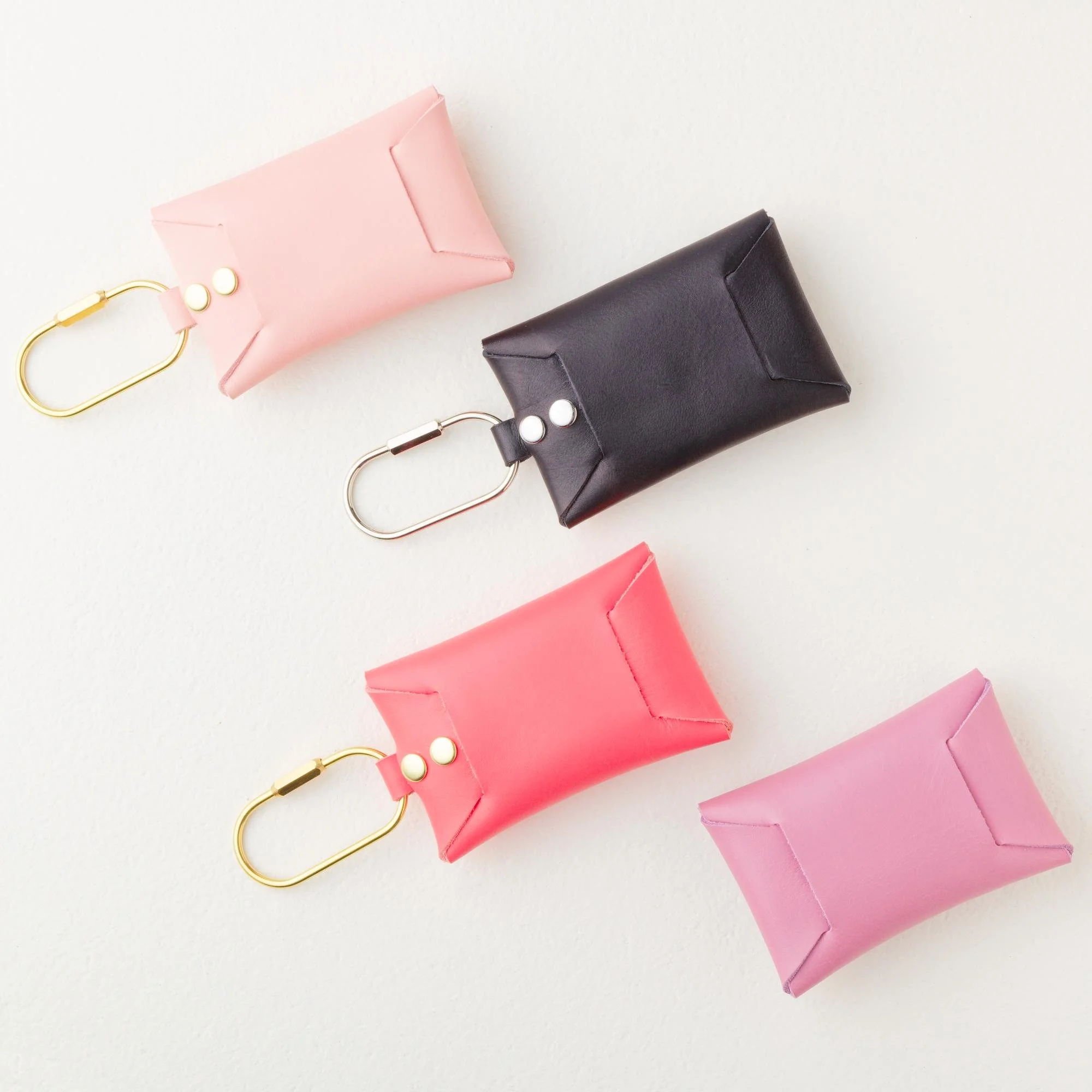 Backside view of set of four personalized leather carabiner keychain wallet pouch / purse charms. Colors include pink, black, purple and coral.